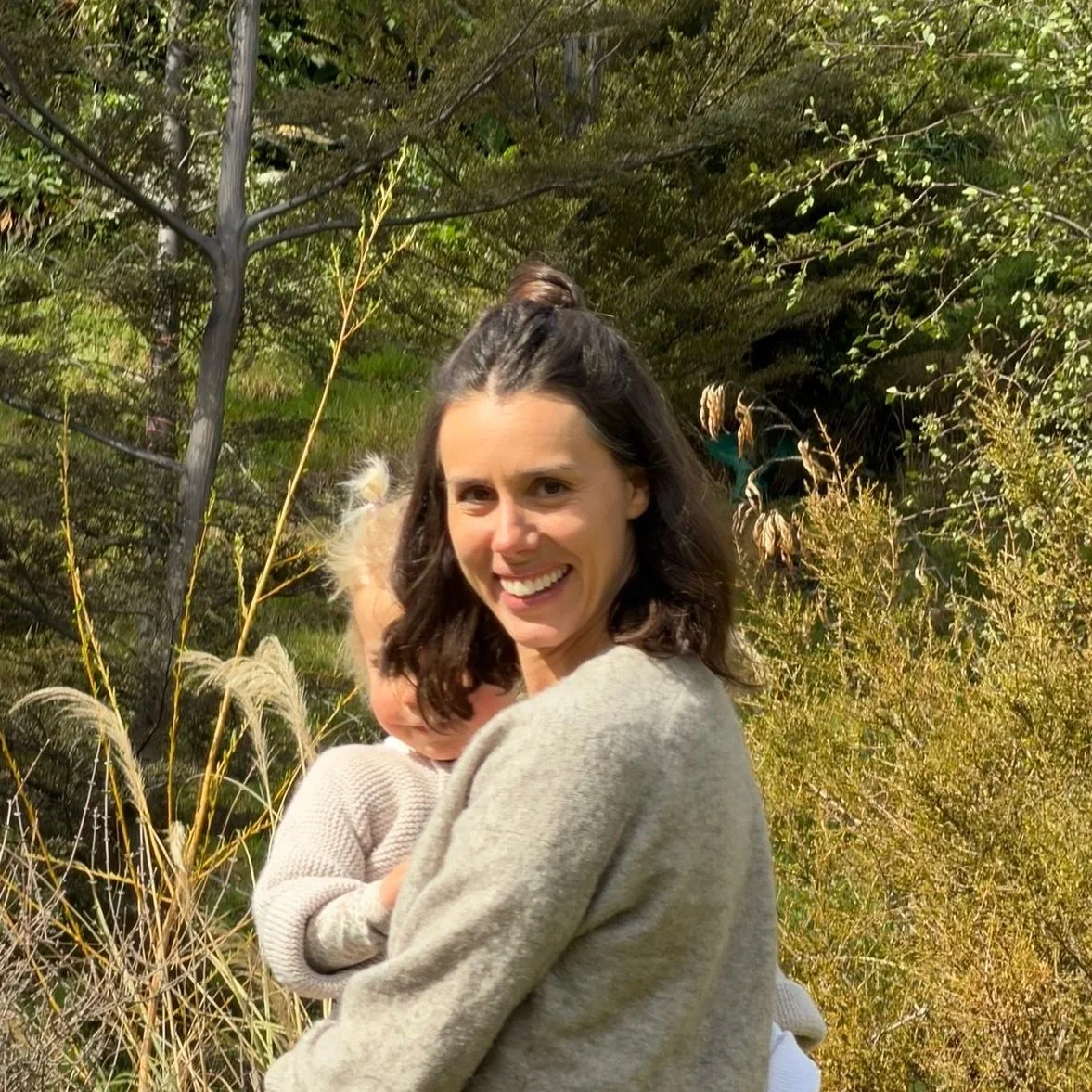 Georgie a Queenstown sleep consultant smiling while holding her daughter.