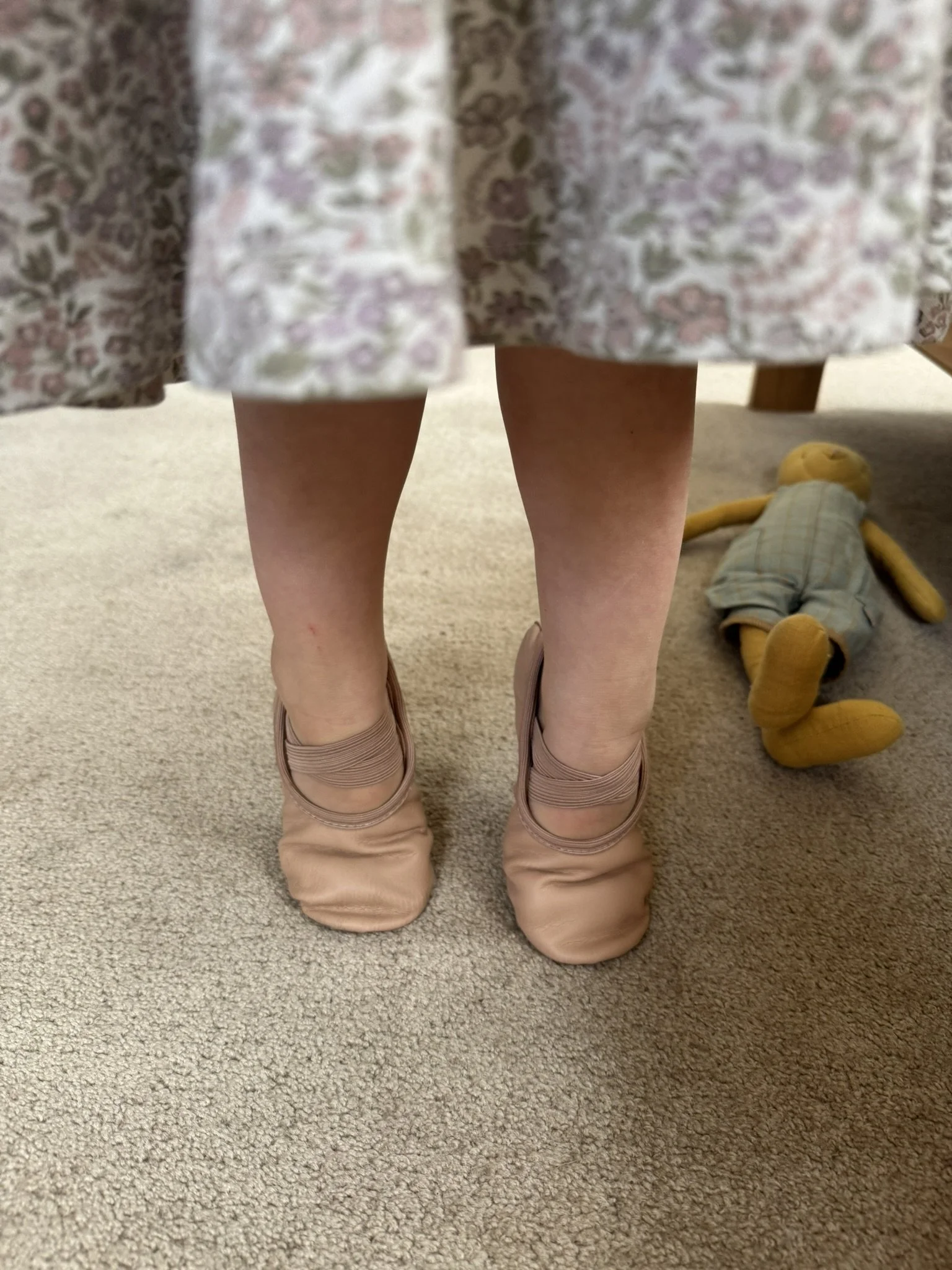 A little girls legs and feet up on tip toes on the carpet.