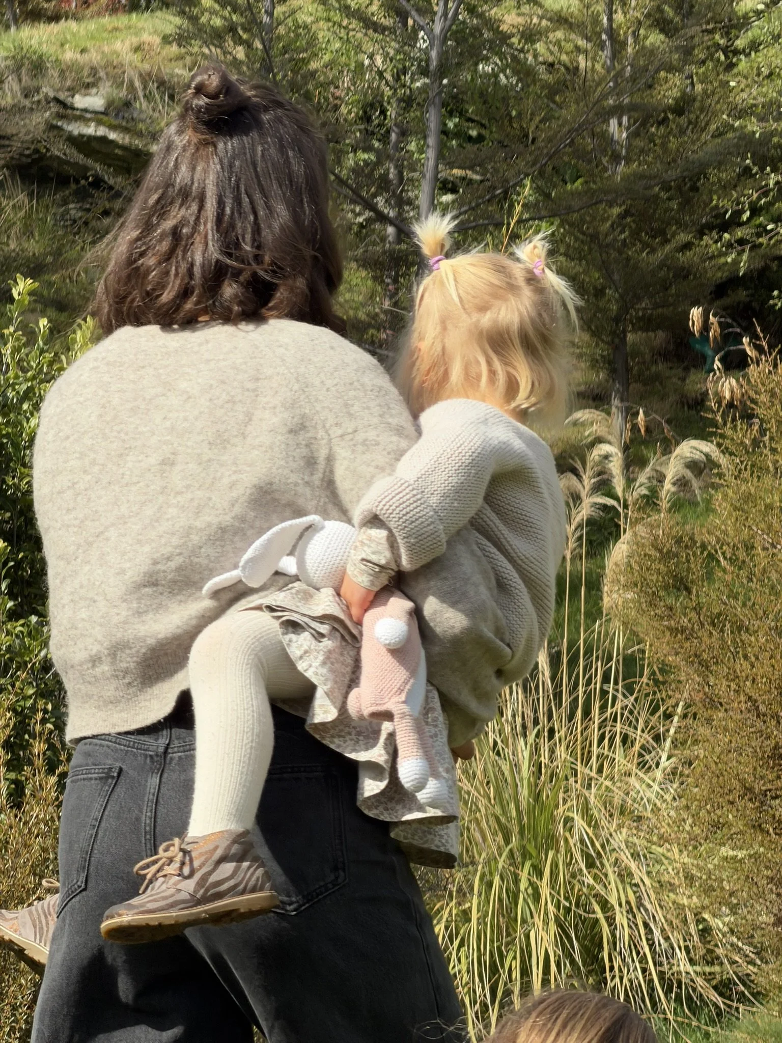 Georgie walking through the garden while holding her daughter.