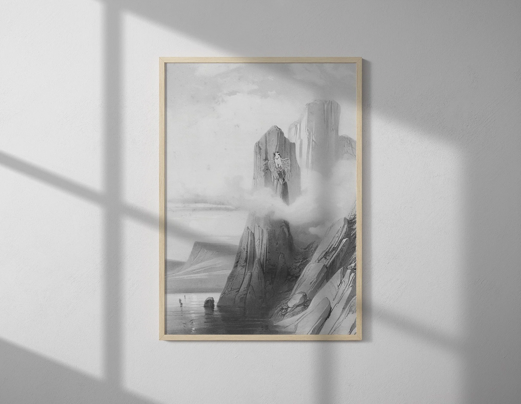 A black and white landscape painting framed in light wood, depicting a griffin on top of rocky cliffs, a lake, and clouds in the sky.