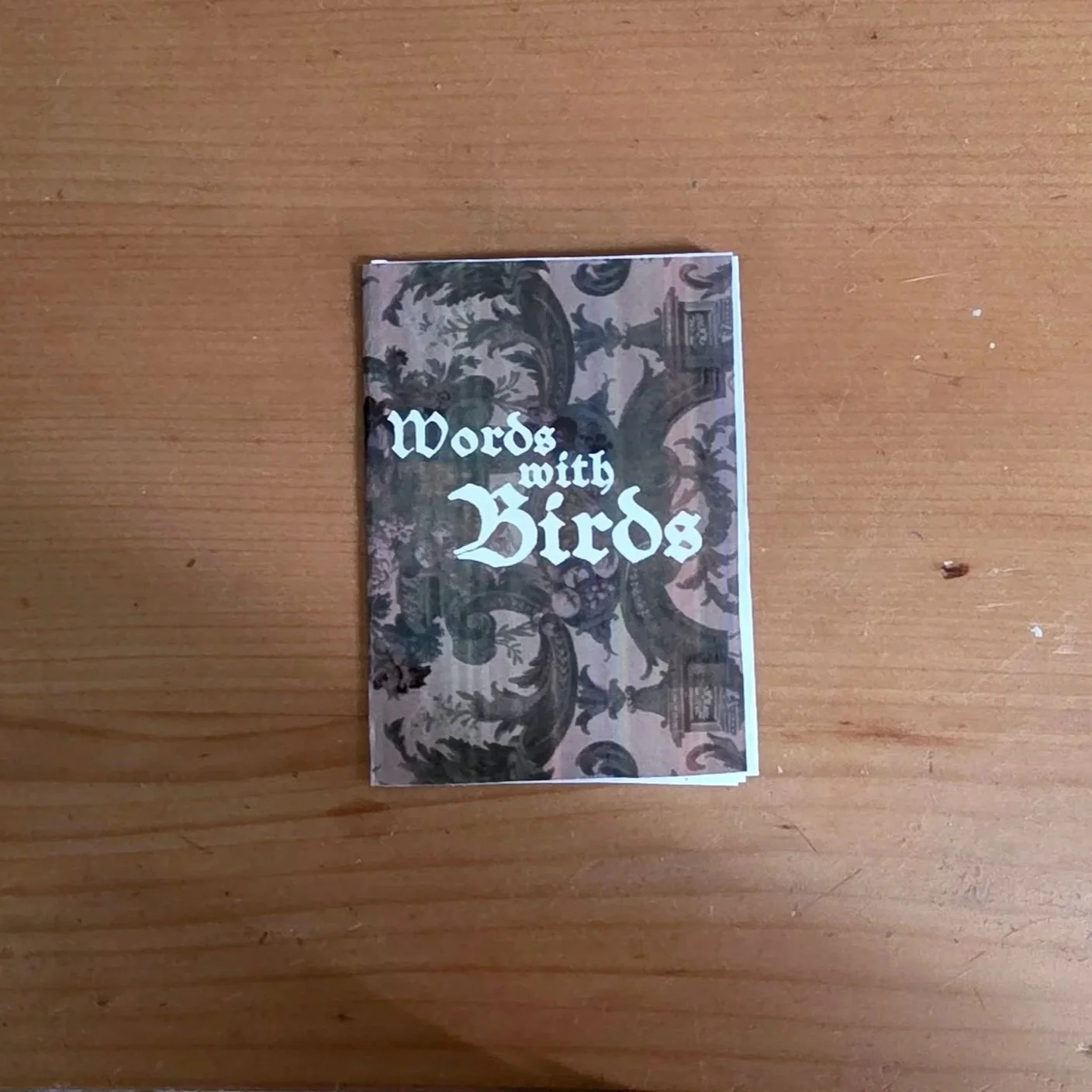 Miniature book titled 'Words with Birds' resting on a wooden surface.