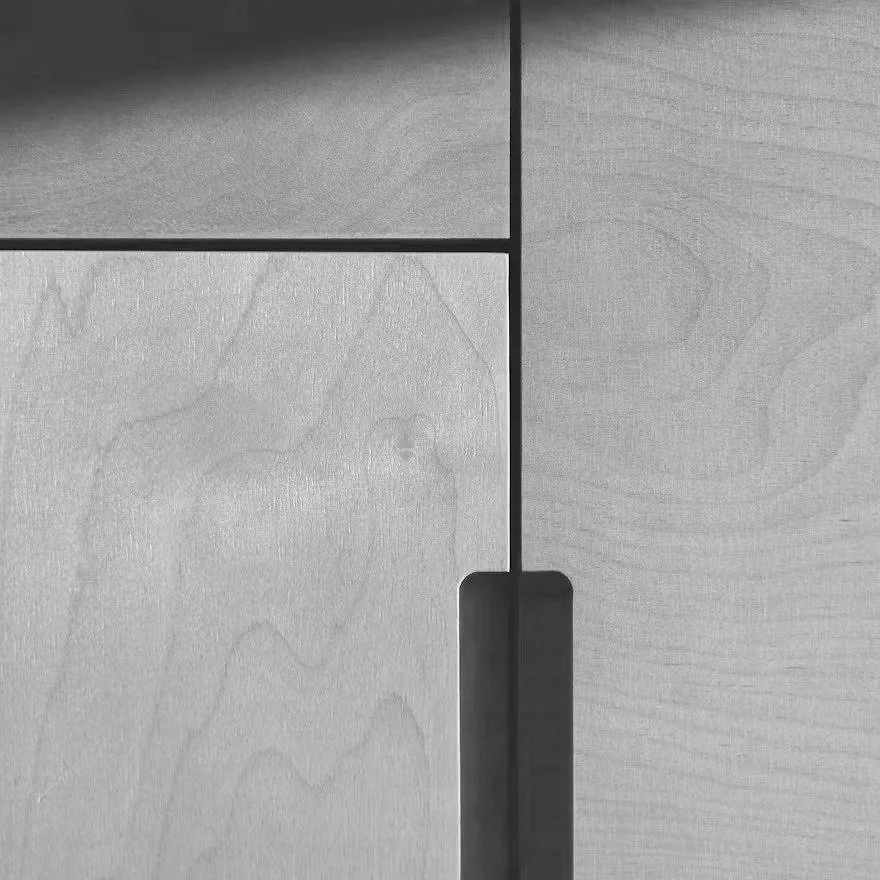 Close-up of a wooden cabinet with a cut-out handle and a black horizontal and vertical line dividing the wood panels.