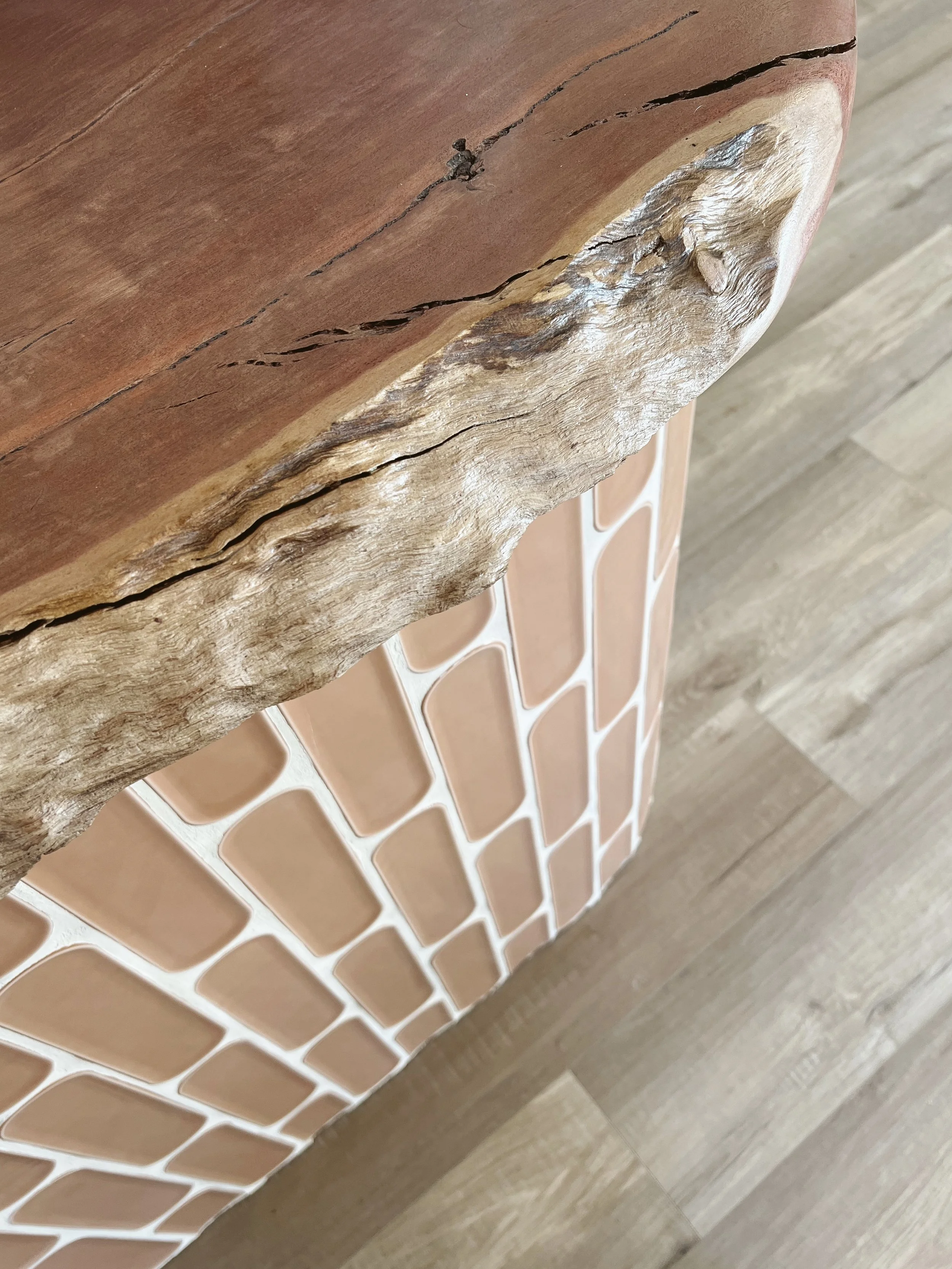 Close-up of a cracked wooden surface with a visible knot, next to a wall with a decorative tile pattern.