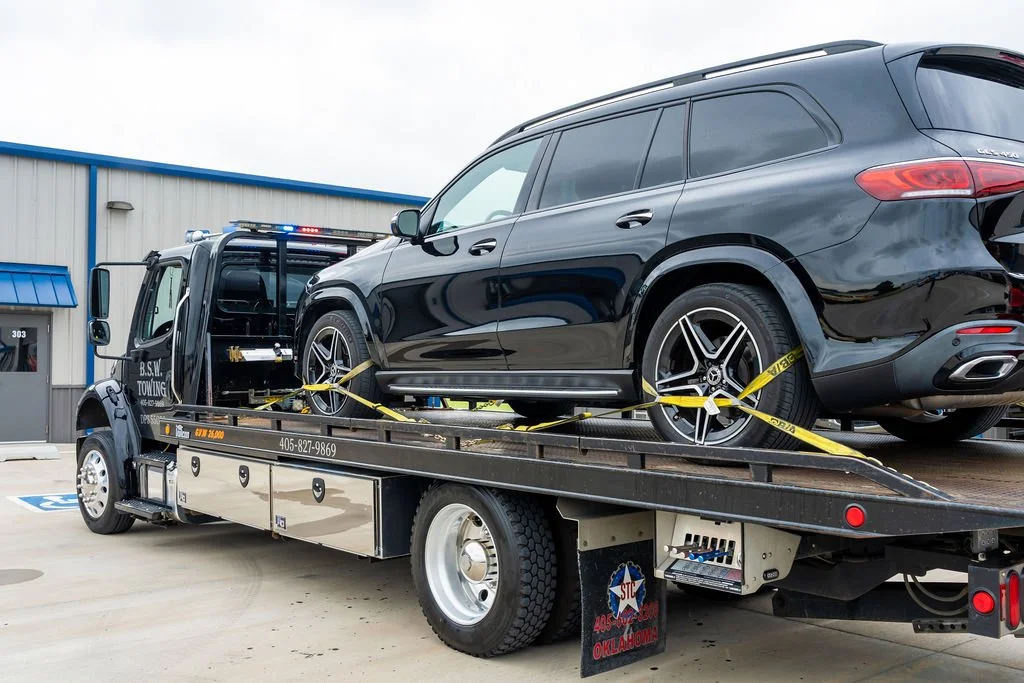 A black SUV loaded onto a flatbed tow truck outside a building.