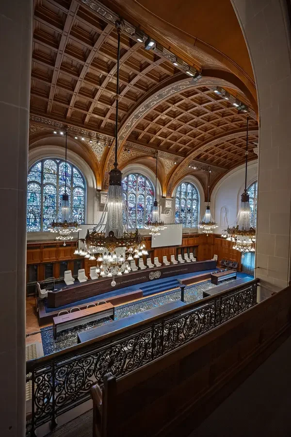View of a historic courtroom or council chamber with high wooden arched ceiling, large stained glass windows, and multiple ornate chandeliers hanging from the ceiling.