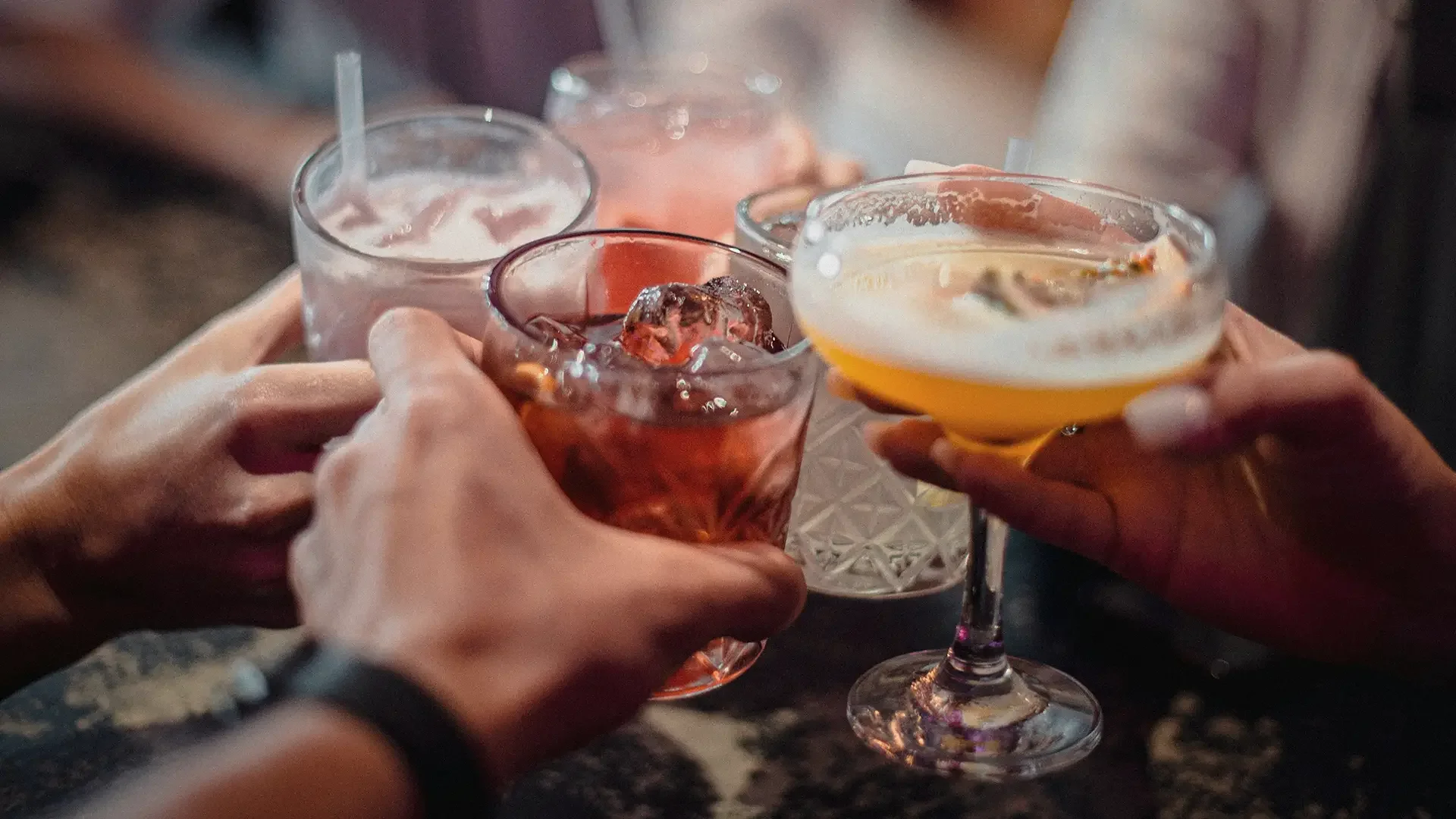 People clinking glasses with various cocktails in a toast during a social gathering at Warfield's restaurant in Clifton Springs, NY.