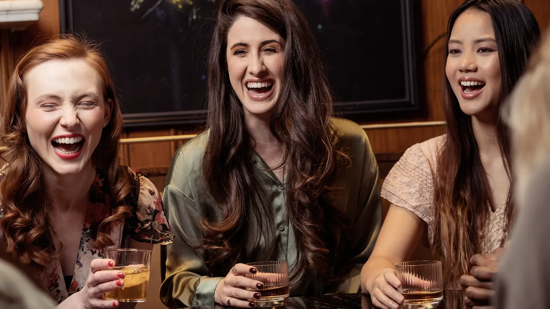 Three women laughing and enjoying drinks at Warfield's restaurant in Clifton Springs, NY.