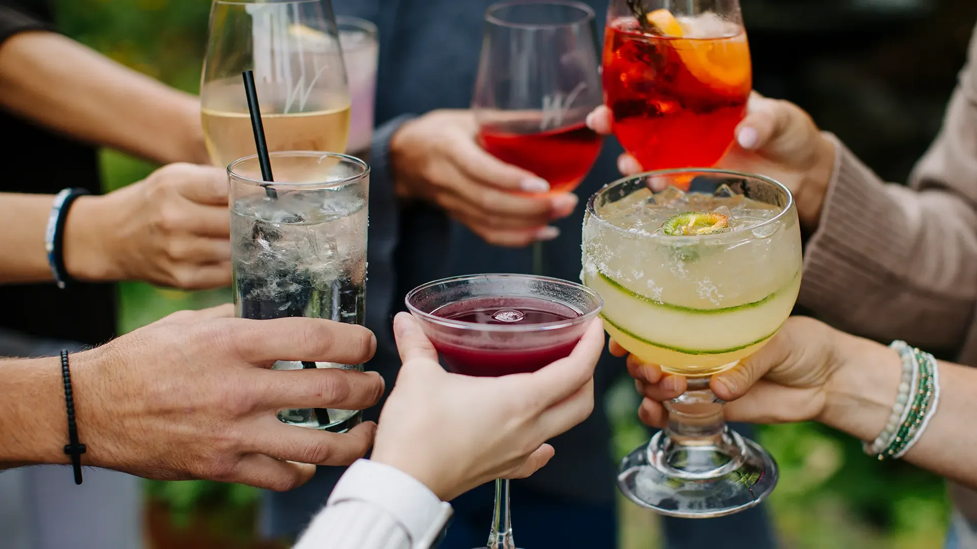 People holding various colorful cocktails and drinks in a toast during a social gathering at Warfield's restaurant in Clifton Springs, NY.