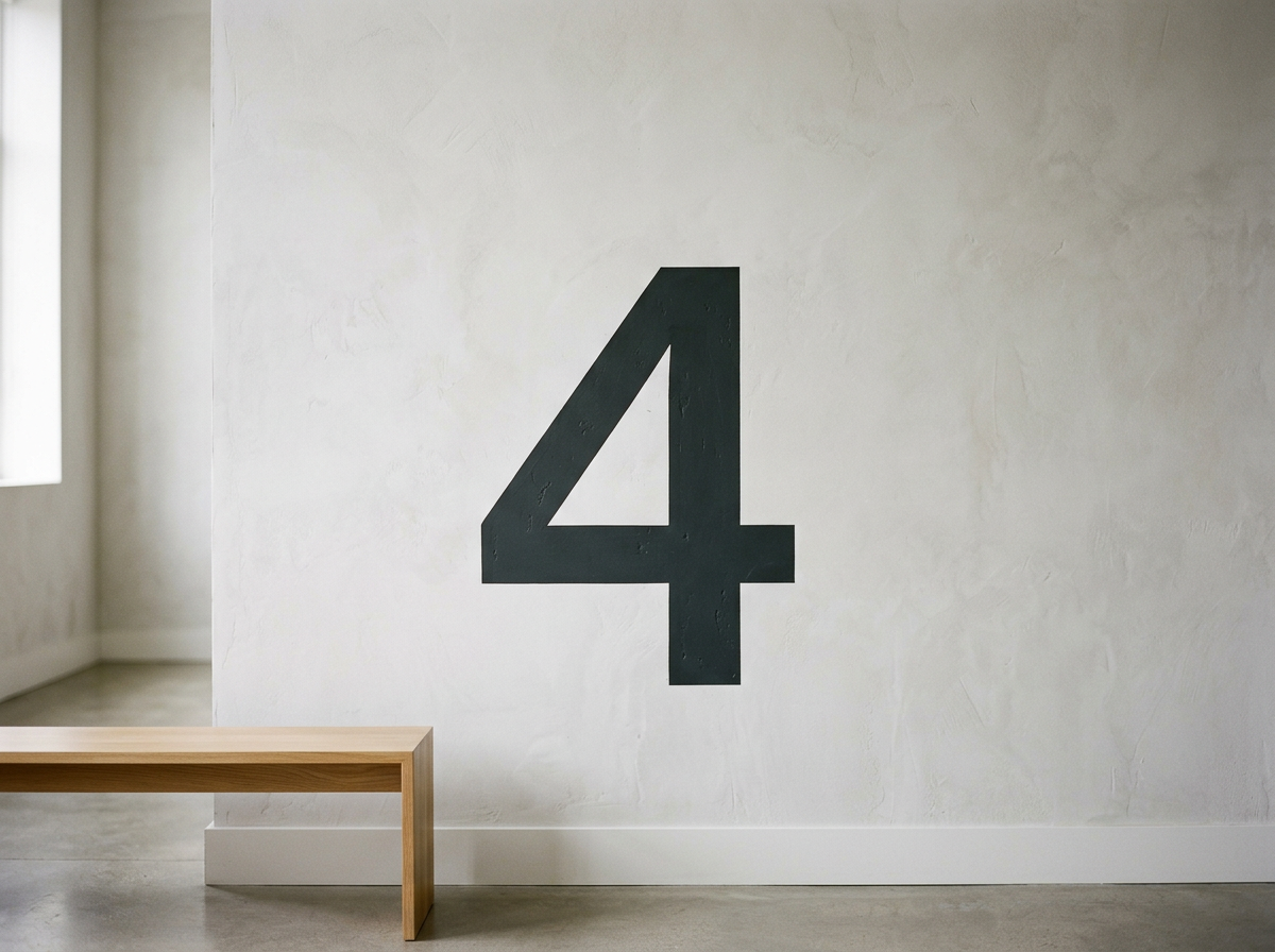 A large black number 4 painted on a plain white wall in a minimalistic room with concrete flooring and a wooden bench