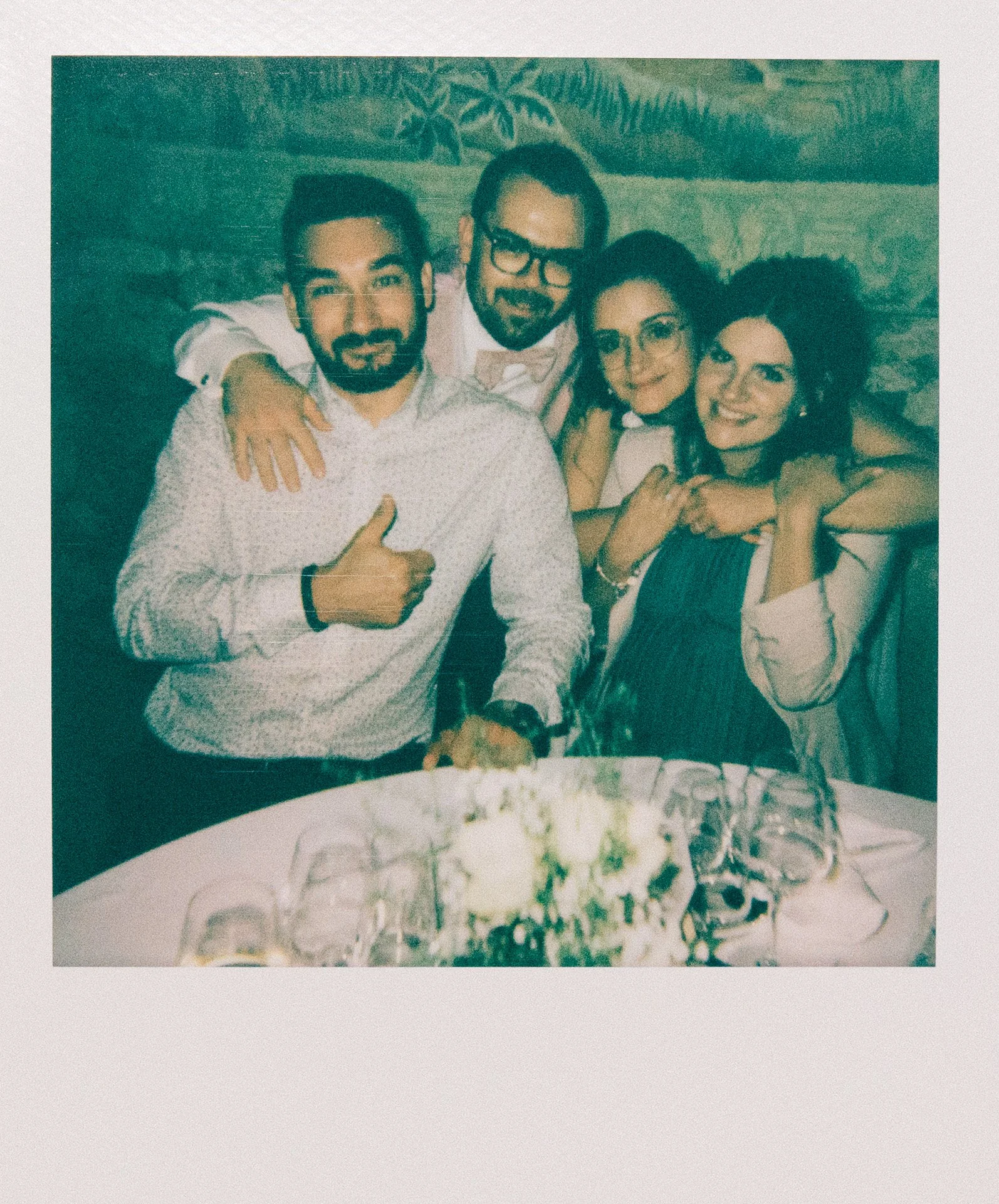 Groupe de cinq personnes souriantes et posant pour une photo dans un restaurant ou un bar, avec un gâteau au centre de la table.