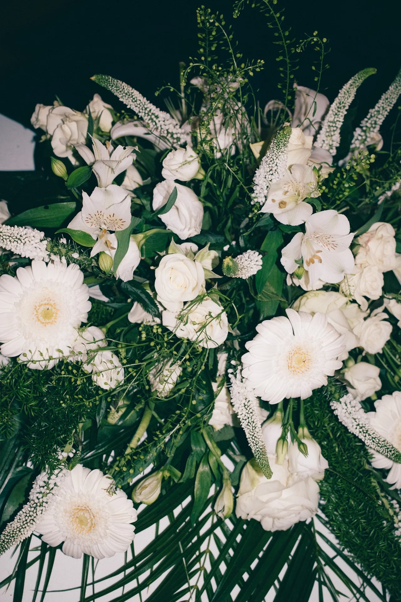 Un arrangement floral avec des fleurs blanches et des feuilles vertes.