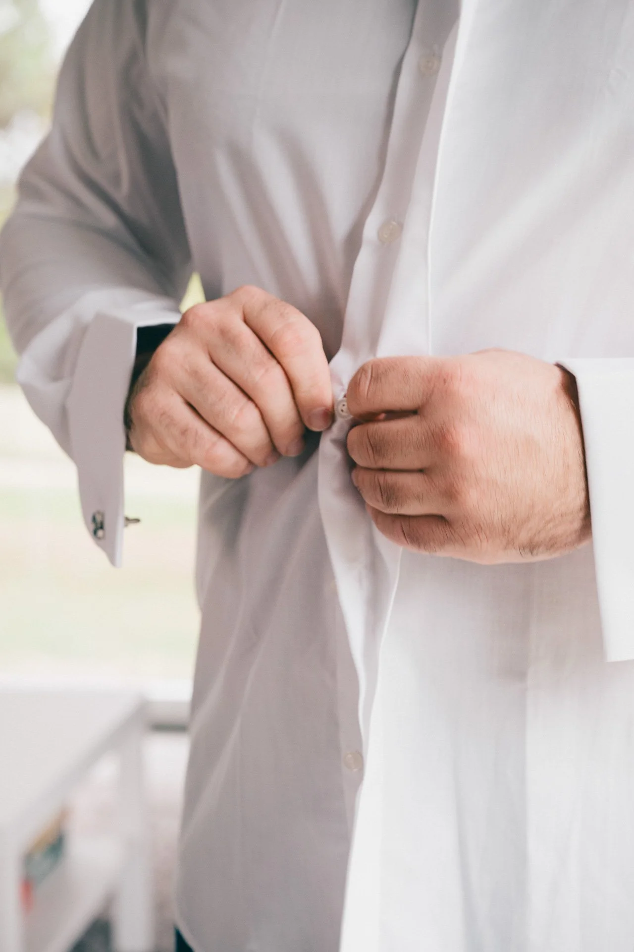 Une personne en train de boutonner une chemise blanche.