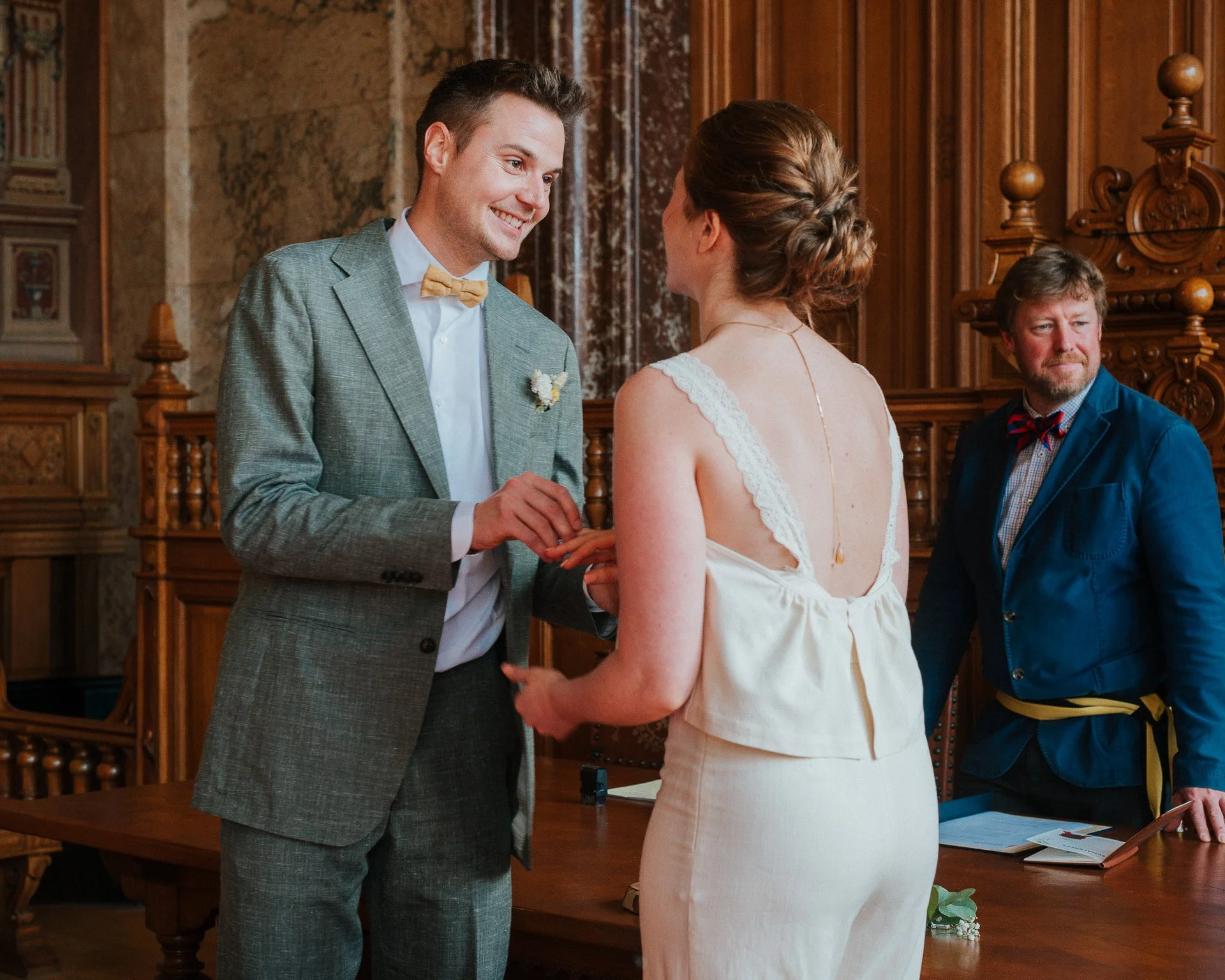 Un couple échange des vœux lors d'une cérémonie de mariage dans une salle ornée de bois.