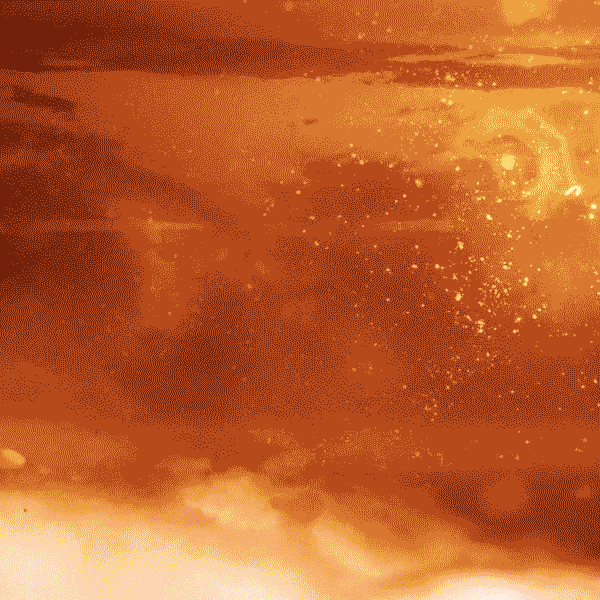 Close-up of swirling golden and amber-colored particles and light.
