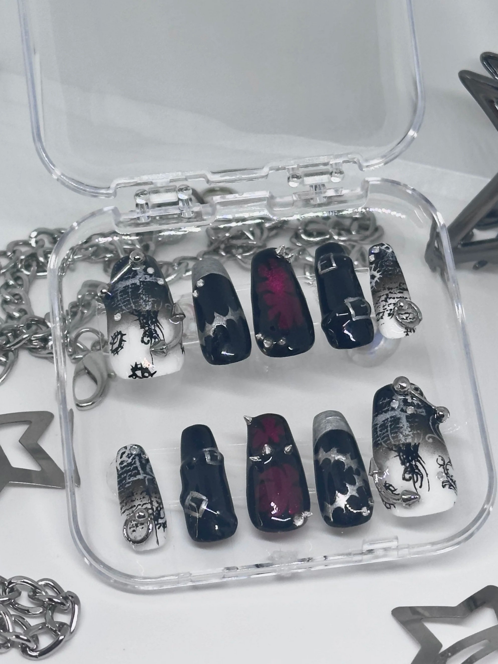 Display case with black, white, and red nail polish bottles and silver chains