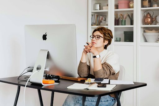 A woman seated at a desk with a computer, focused on her career transition and planning her next steps.