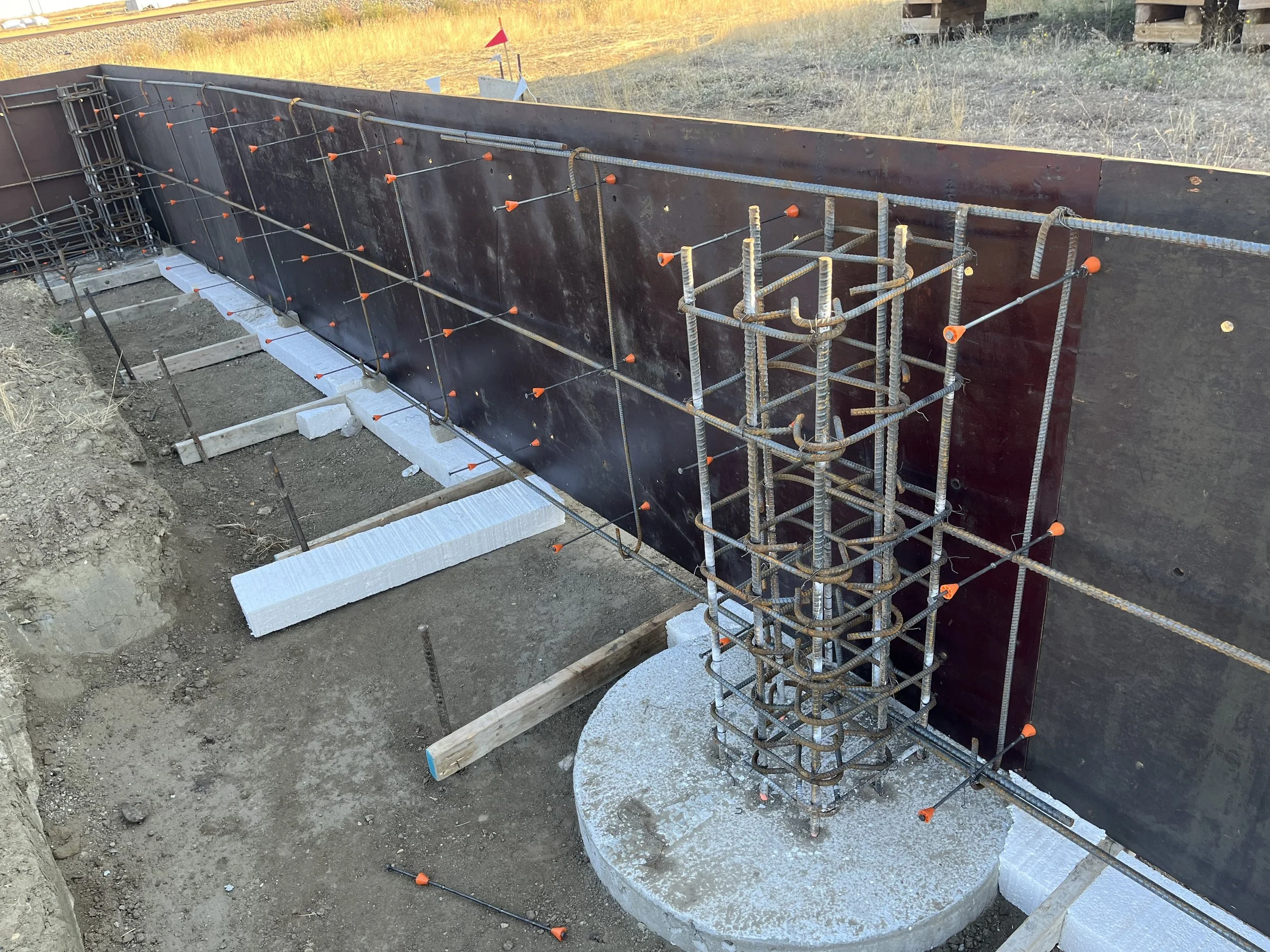 Construction site with concrete foundation, metal rebar, and wooden supports for a building.
