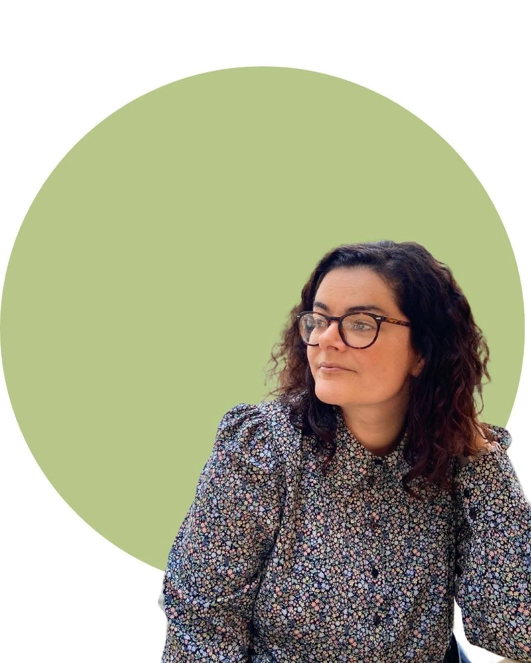 A woman with curly dark hair and glasses looking to her left, wearing a floral patterned blouse, with a light green circle behind her.