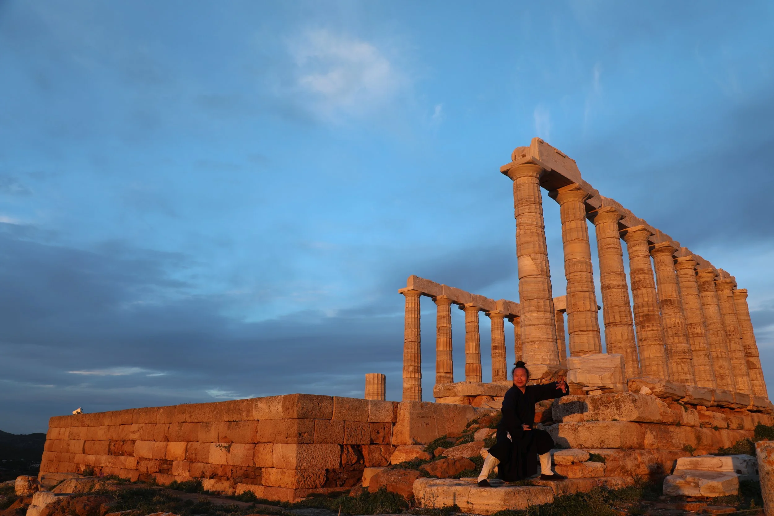 Wudang Gong Dao practitioner performing a martial arts stance in front of ancient Greek temple ruins