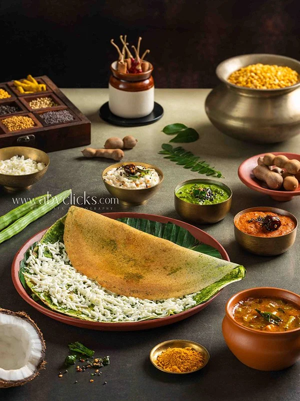 Indian food spread with a dosa on a large plate, various chutneys and curries, rice, spices, ginger, and vegetables
