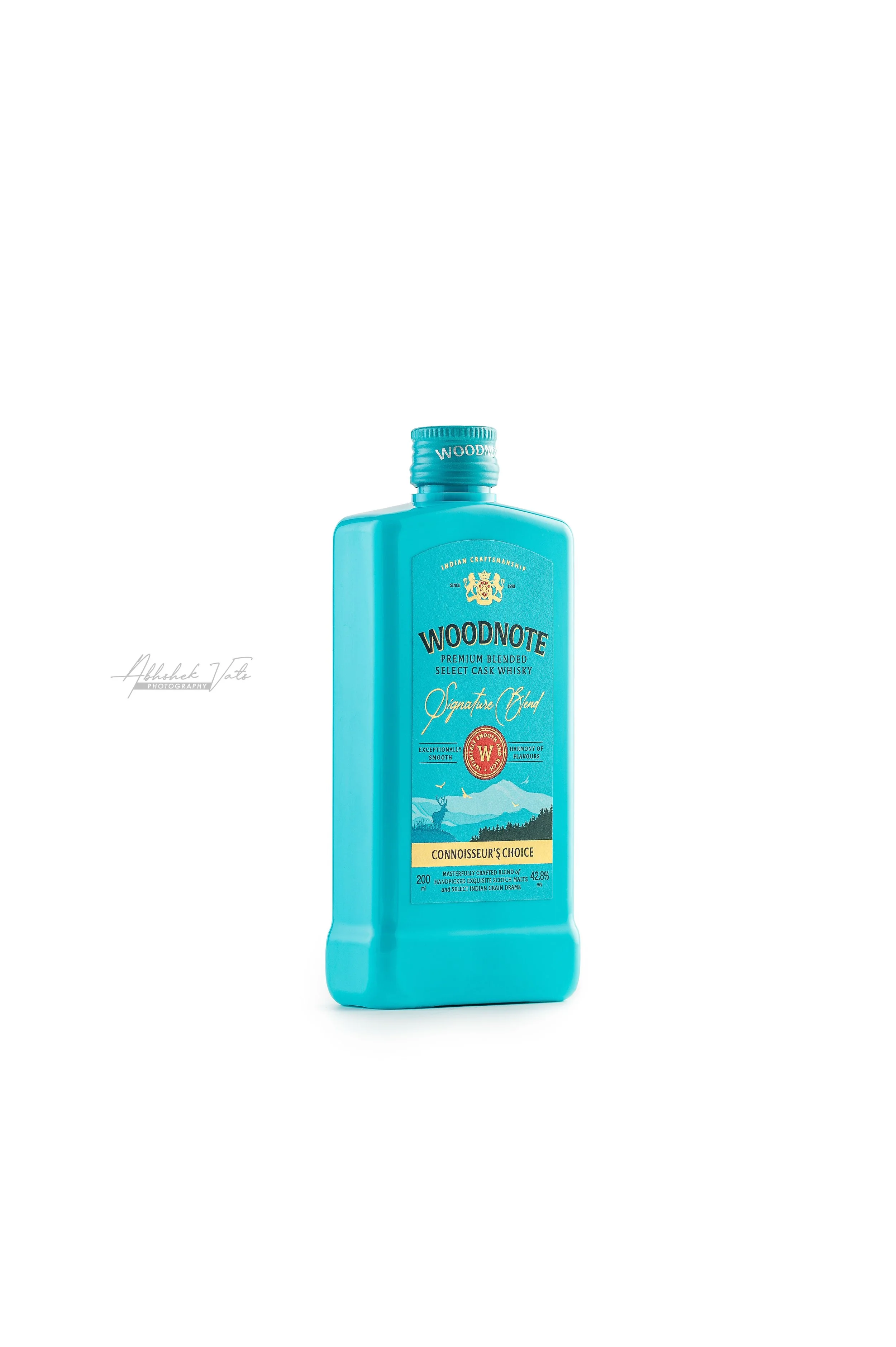 A blue bottle of Woodnote Connoisseur's Choice Indian grain whisky against a white background.