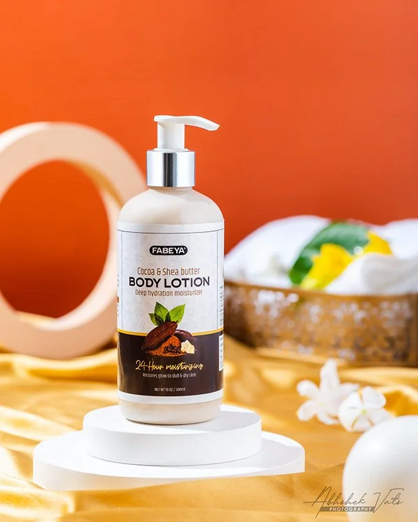 Bottle of Fabeya cocoa and shea butter body lotion with pump dispenser on a display stand, in a spa or skincare setting.