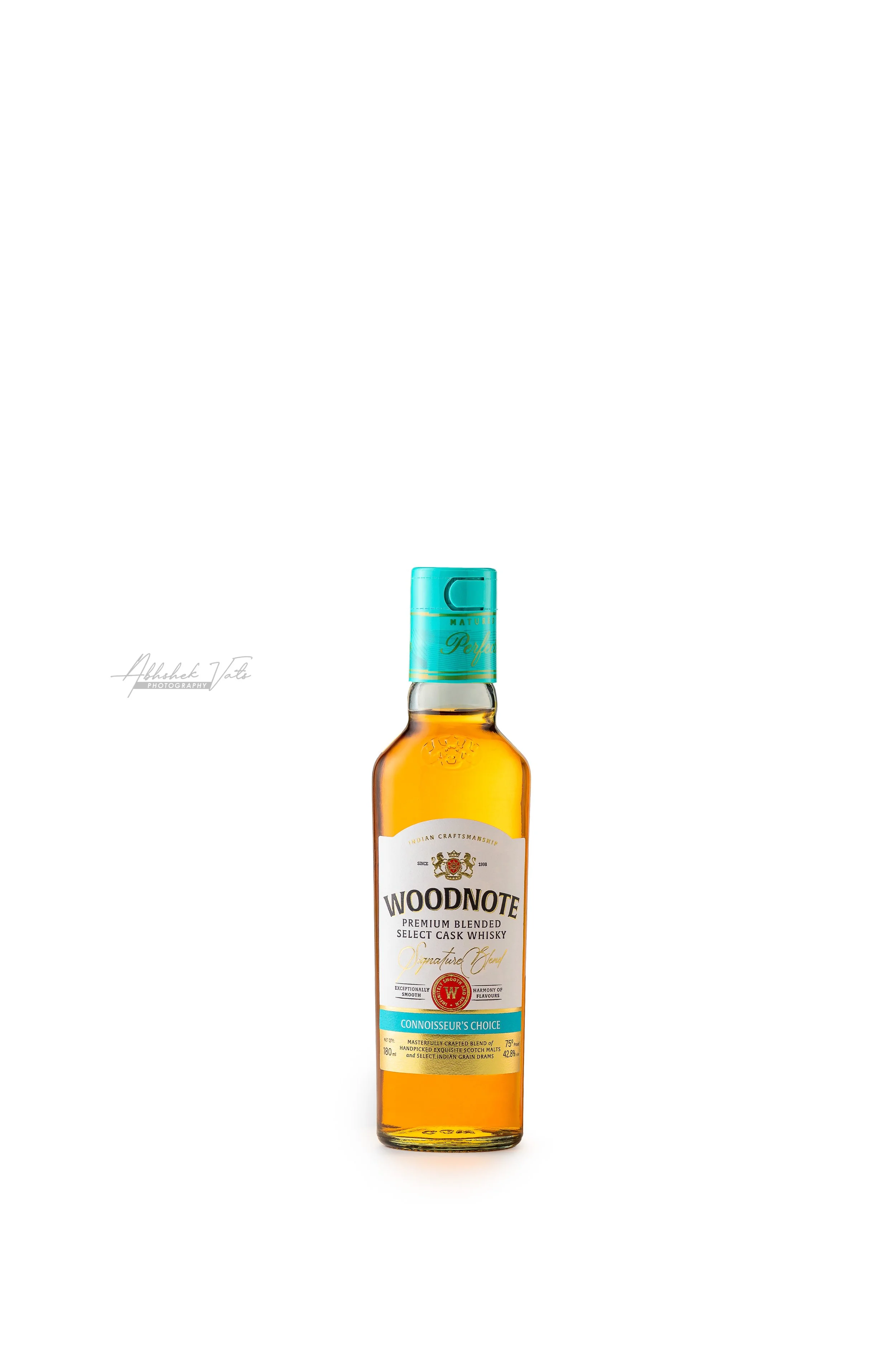Bottle of Woodnote premium blended whiskey with a blue cap and white label in the center of a white background.