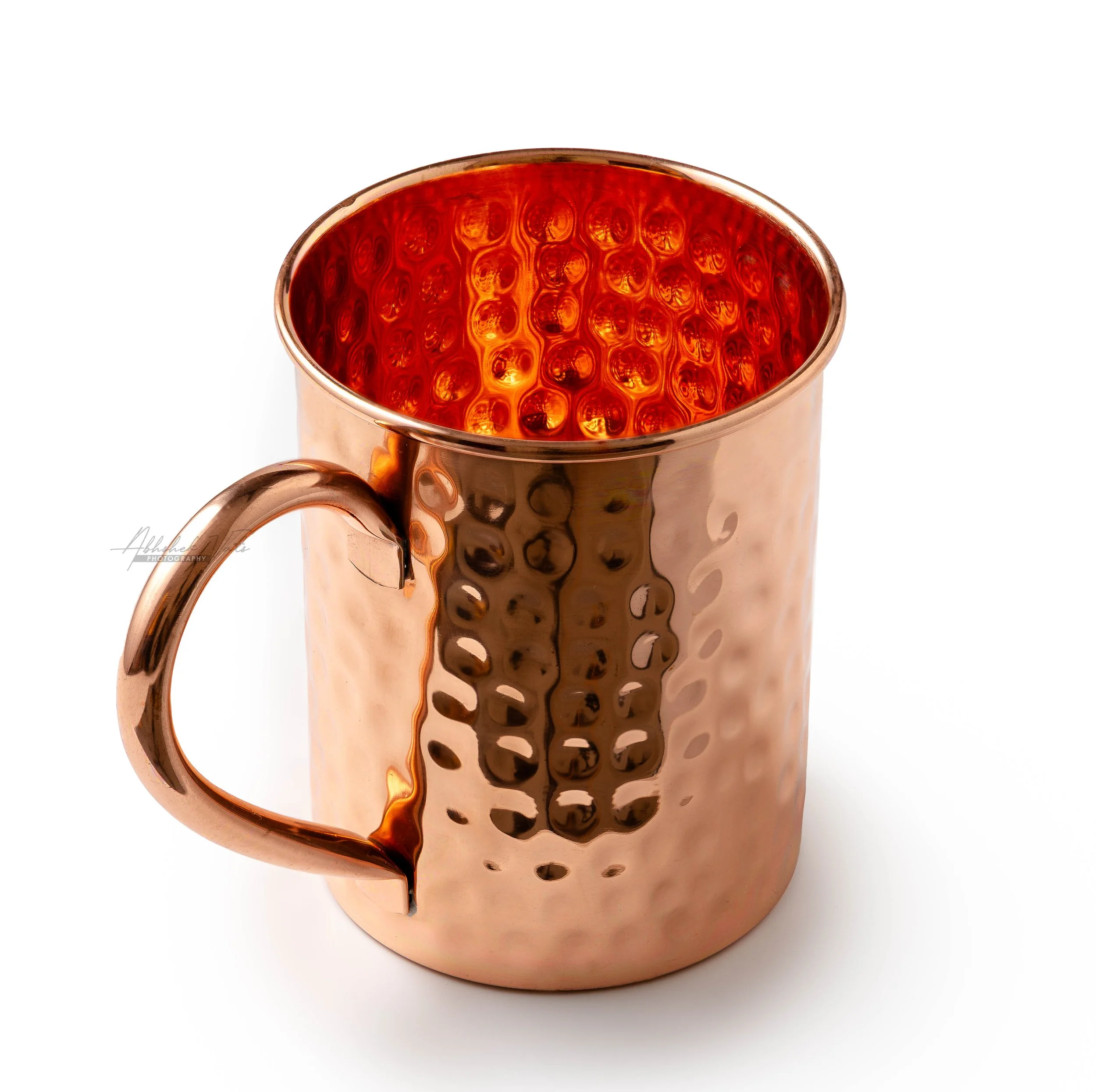 Copper-colored mug with a honeycomb pattern interior, with dark coffee inside, set against a plain white background.