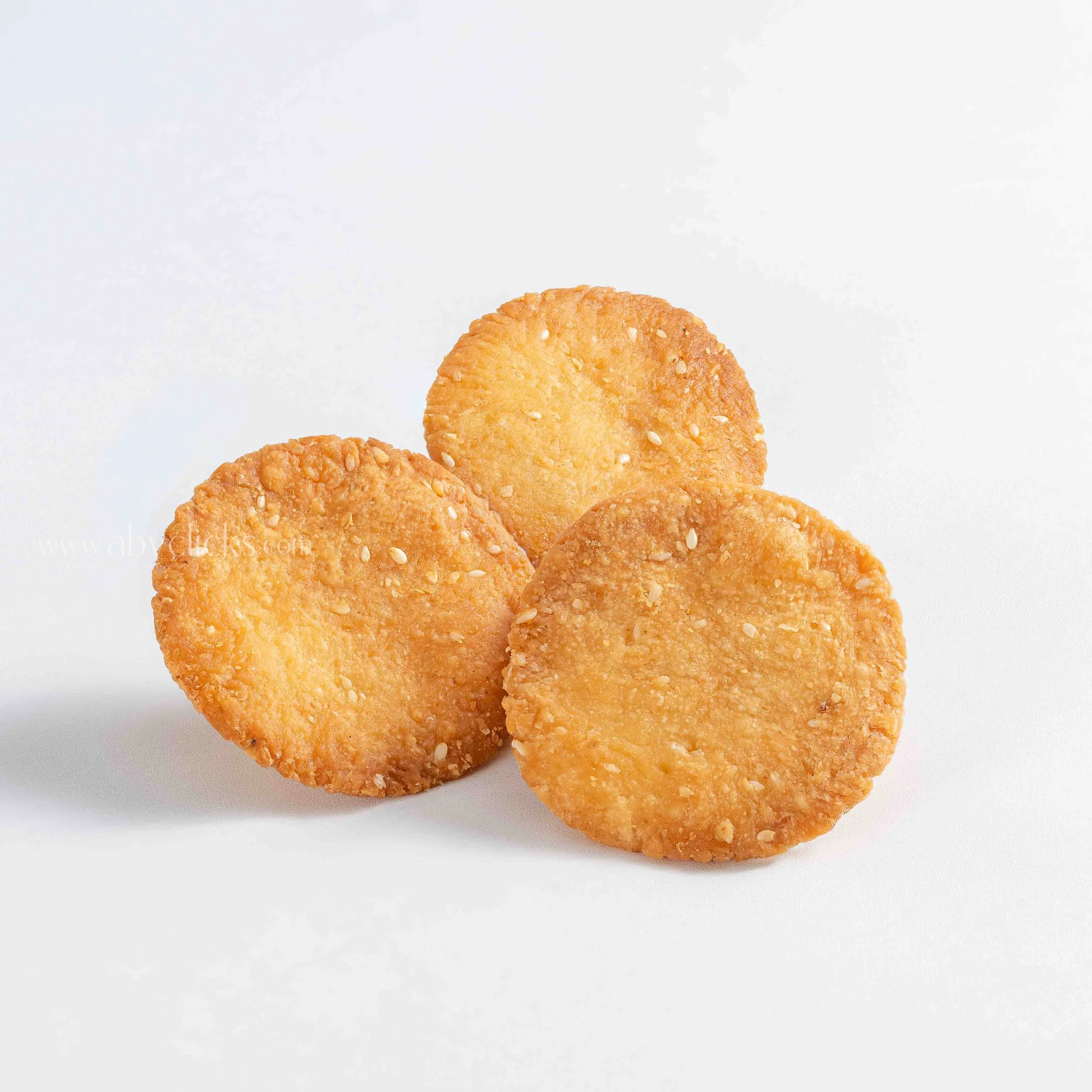 Close-up of crispy, golden-brown potato chips with sesame seeds, on a white background.