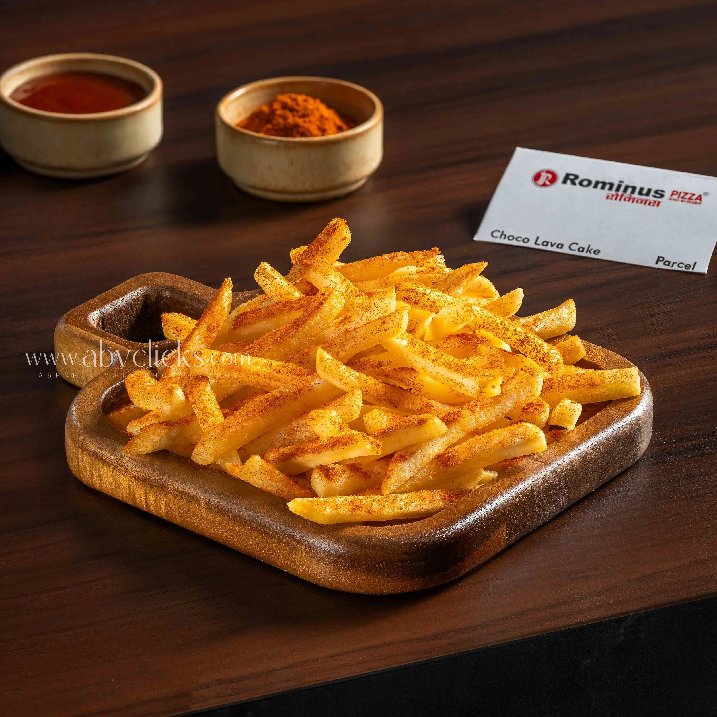 French fries seasoned with orange spice on a wooden plate.