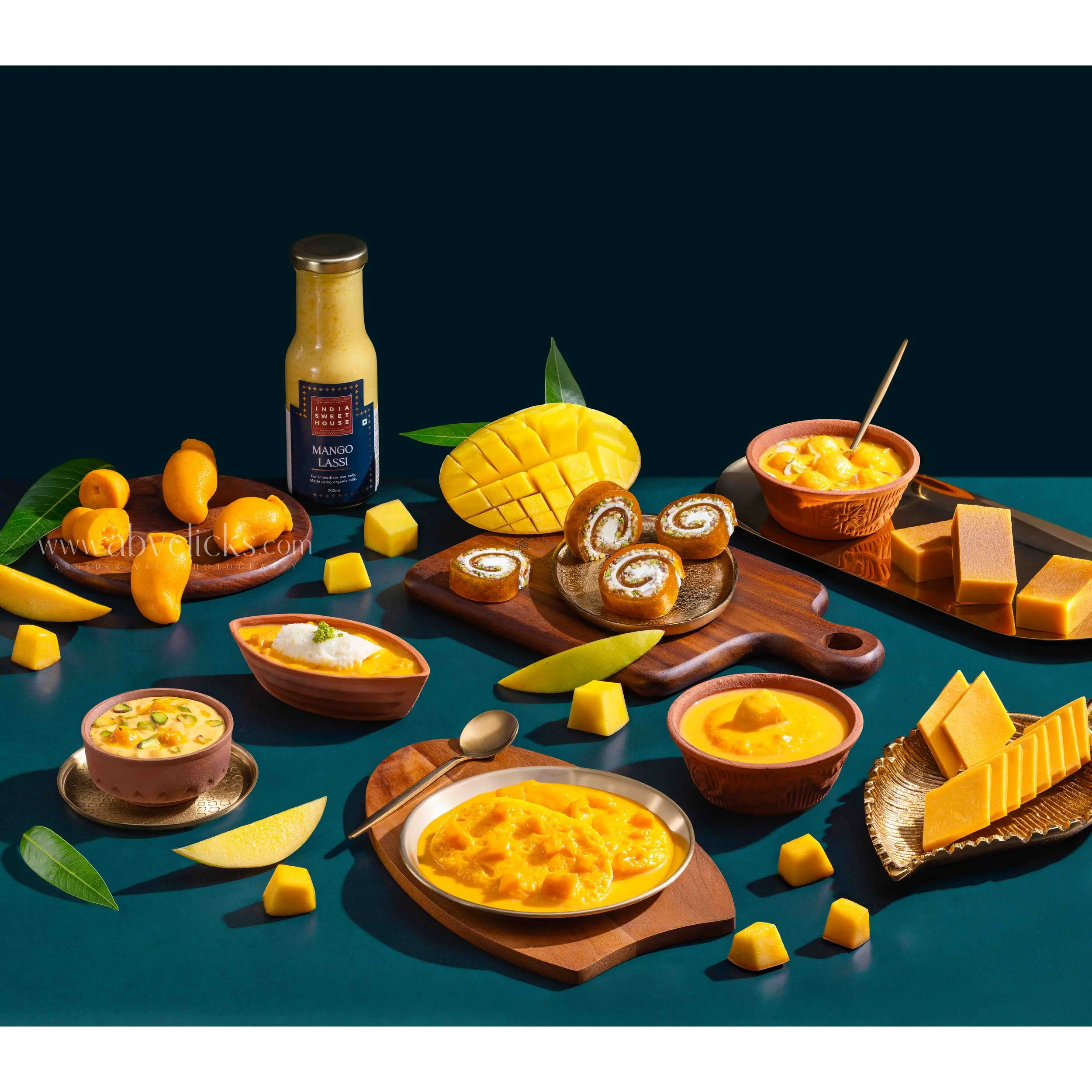 Various mango desserts and sauces on a table with a dark background.
