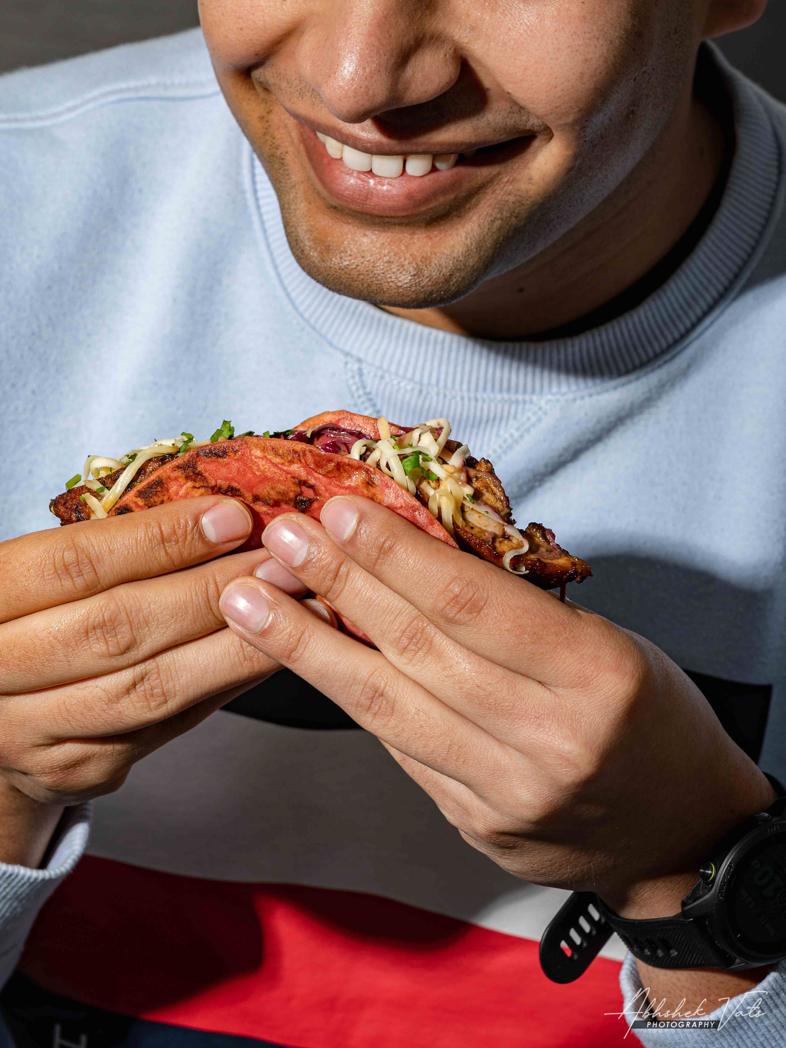 A person holding a taco with tomato, cheese, and shredded lettuce.