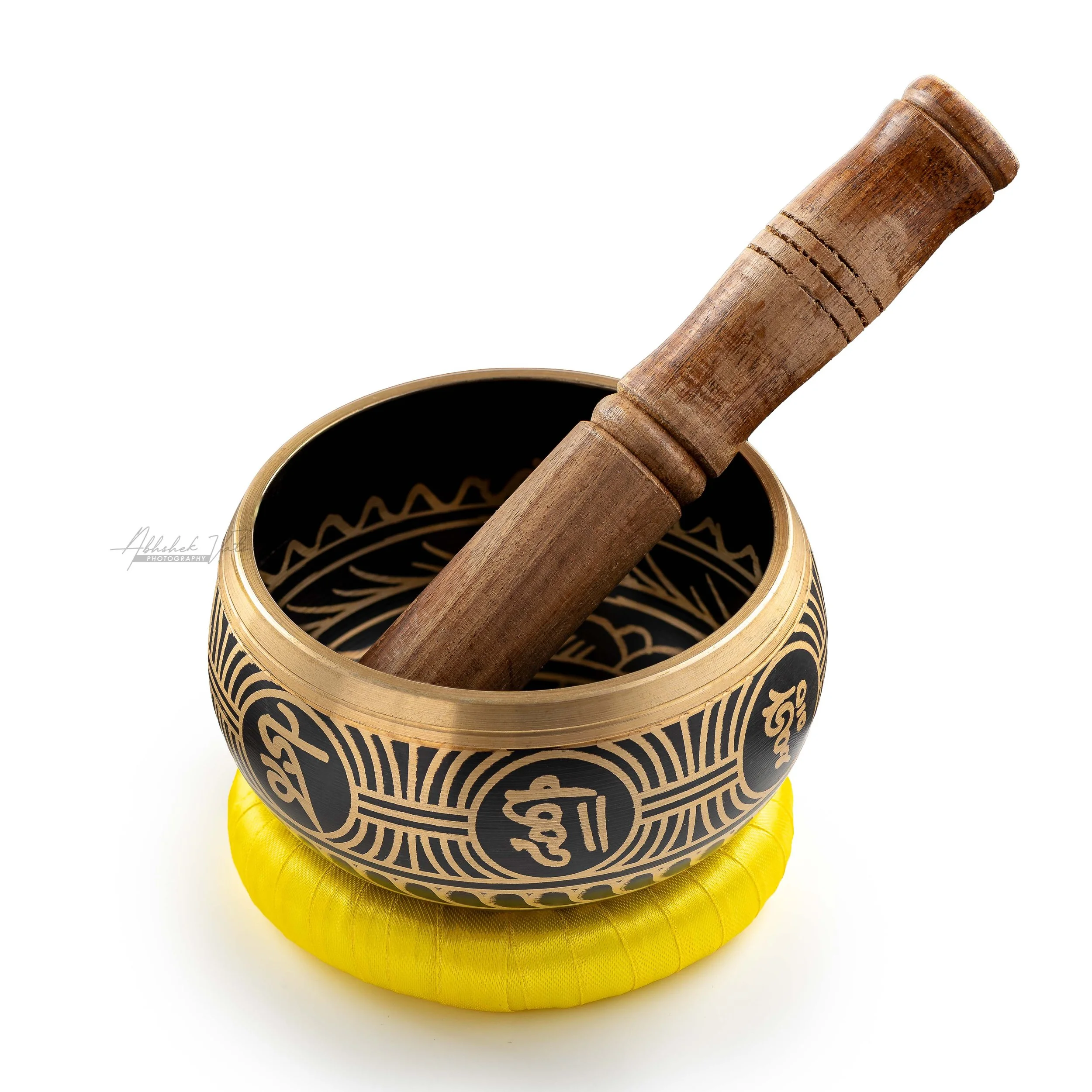 Handcrafted black and gold bamboo drum with intricate patterns resting on yellow fabric.
