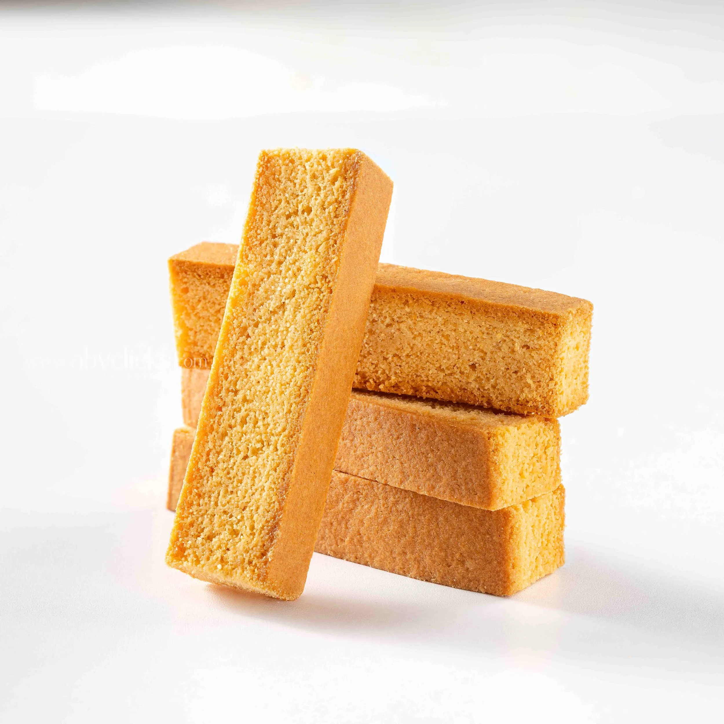 Stacked golden yellow sponge cake slices on a plain white surface.