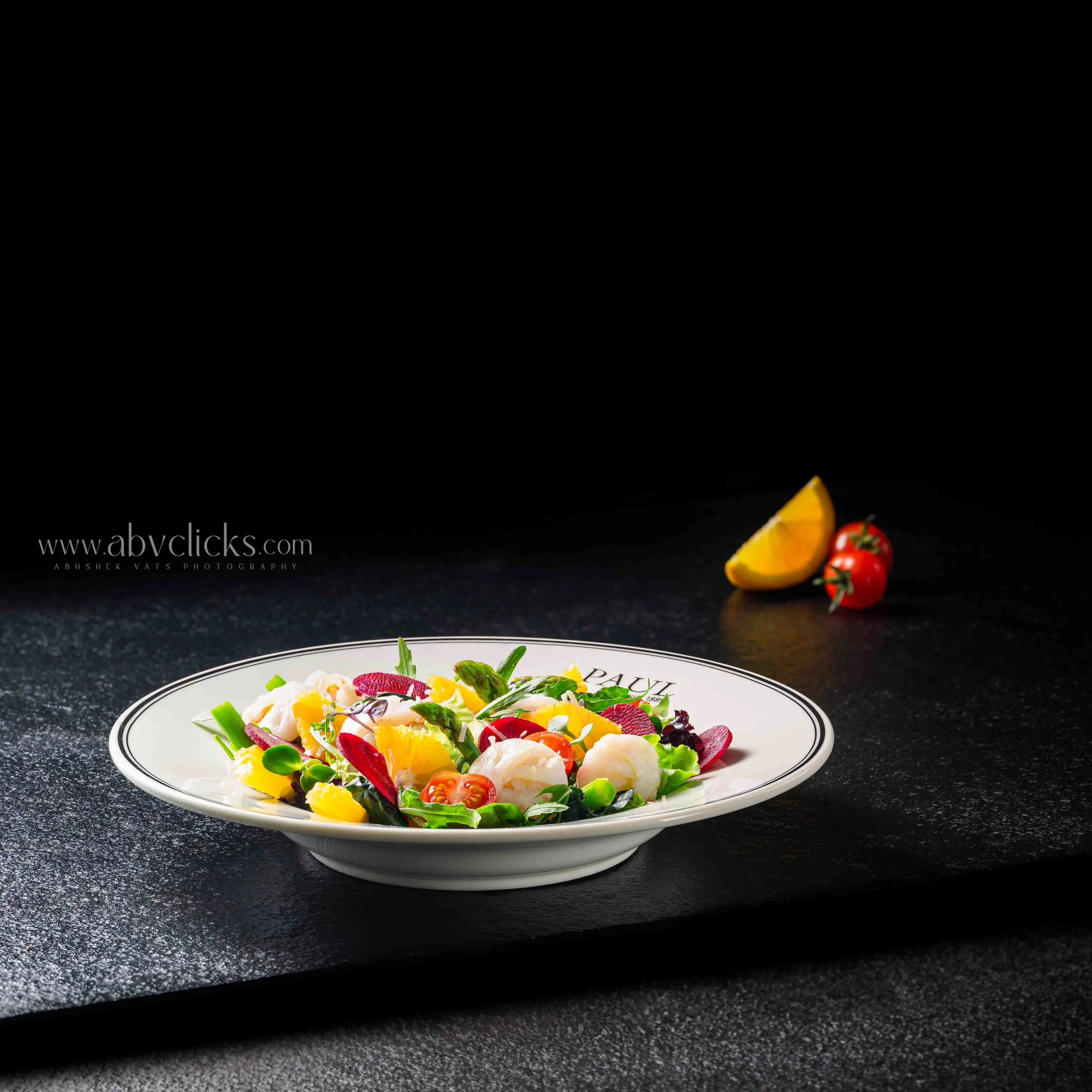 Colorful salad with vegetables served in a white bowl on a dark surface.