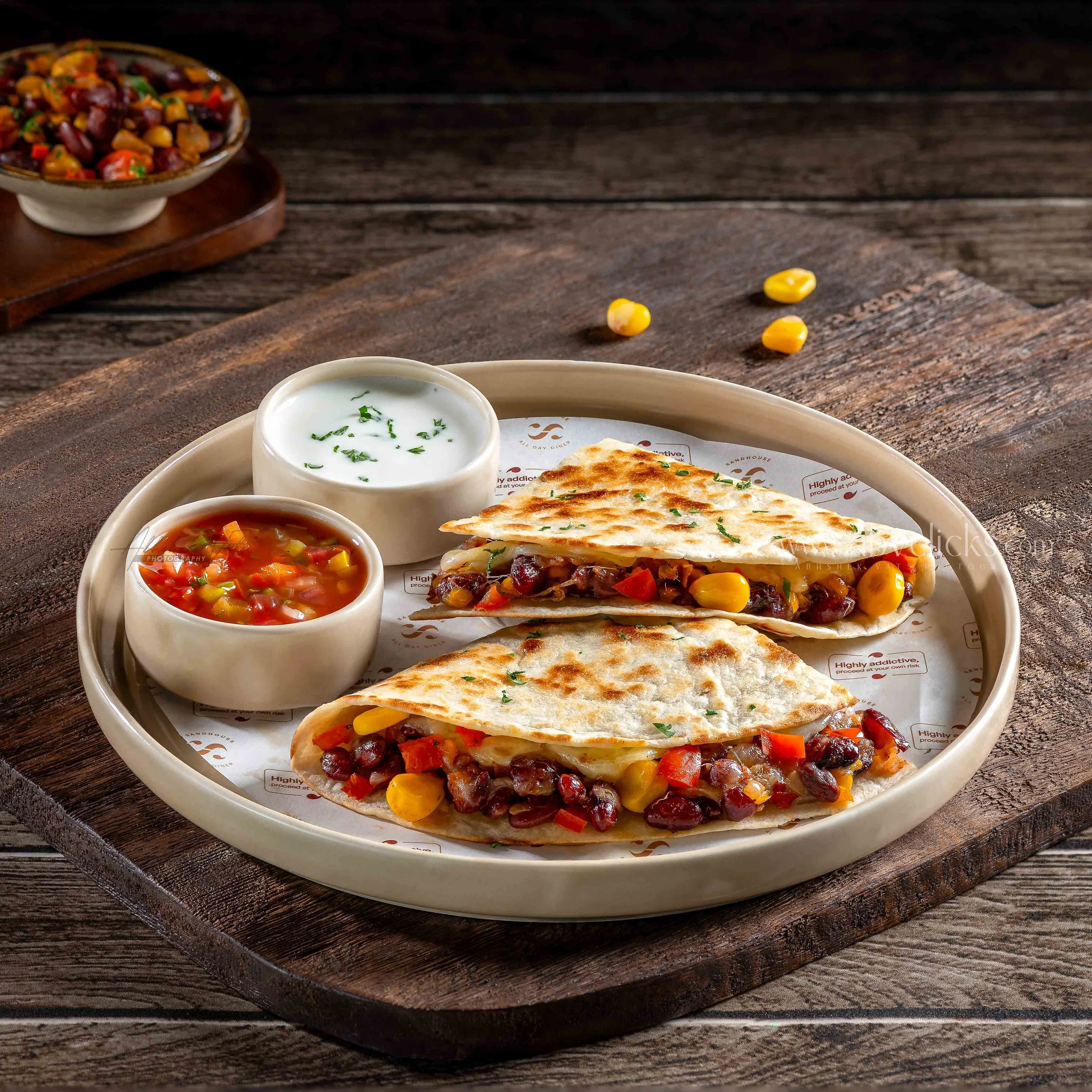 A plate of Indian flatbread served with two small bowls of sauce, one green and one red, on a rustic wooden table.