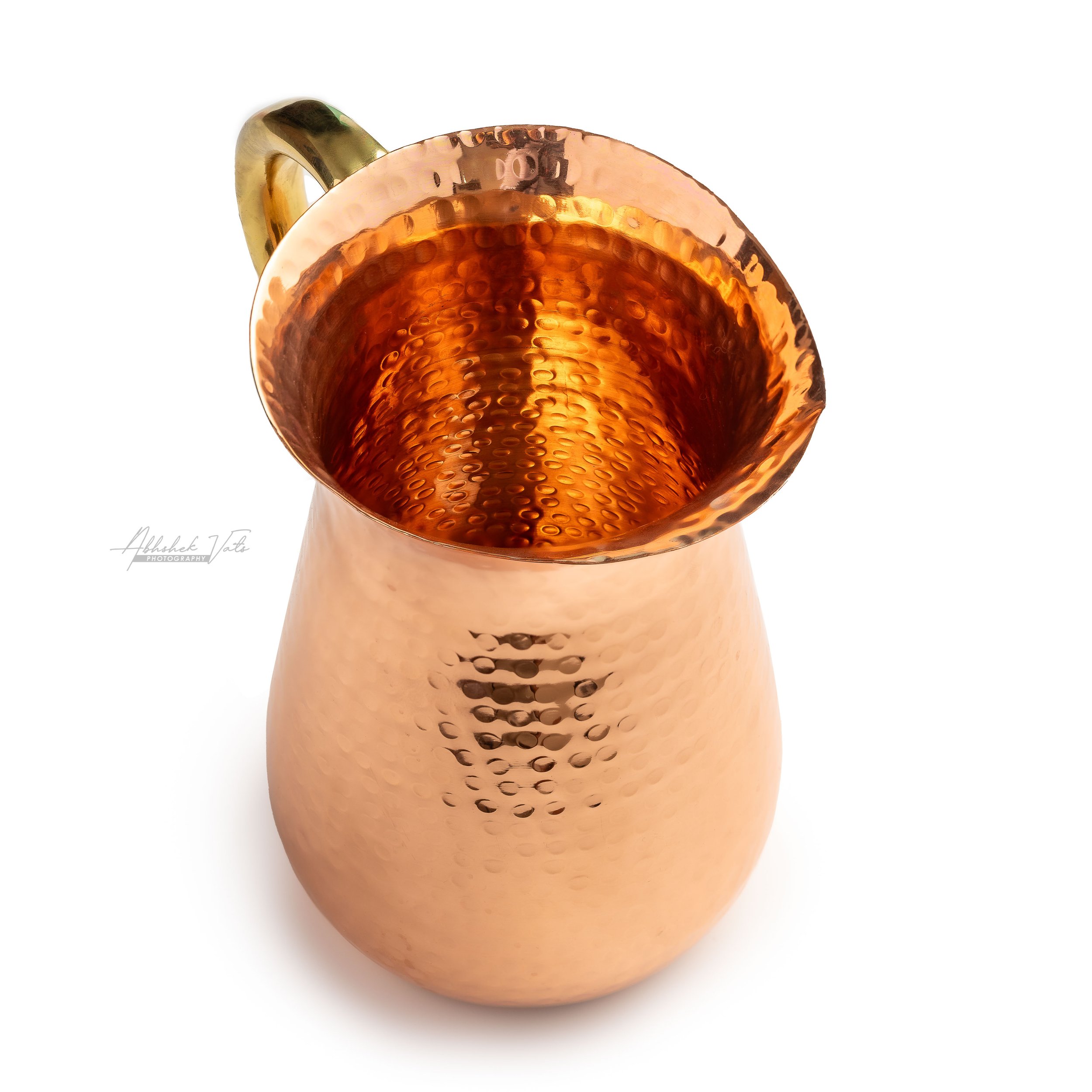 Close-up of a hammered copper mug with a gold handle, isolated on white background.