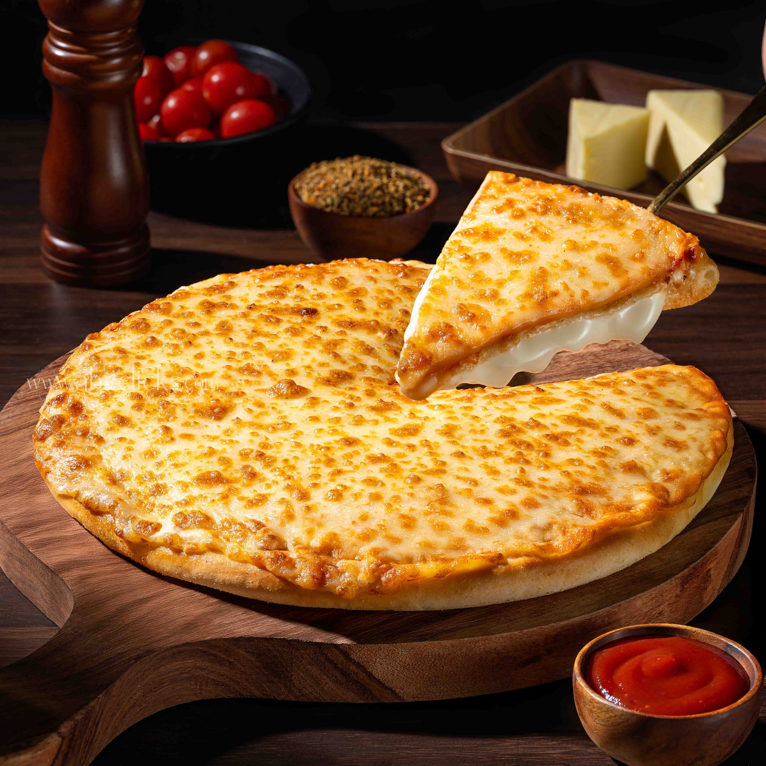 Cheese pizza with a golden crust, on a wooden serving board, with cherry tomatoes, spices, cheese slices, and a bowl of marinara sauce in the background.