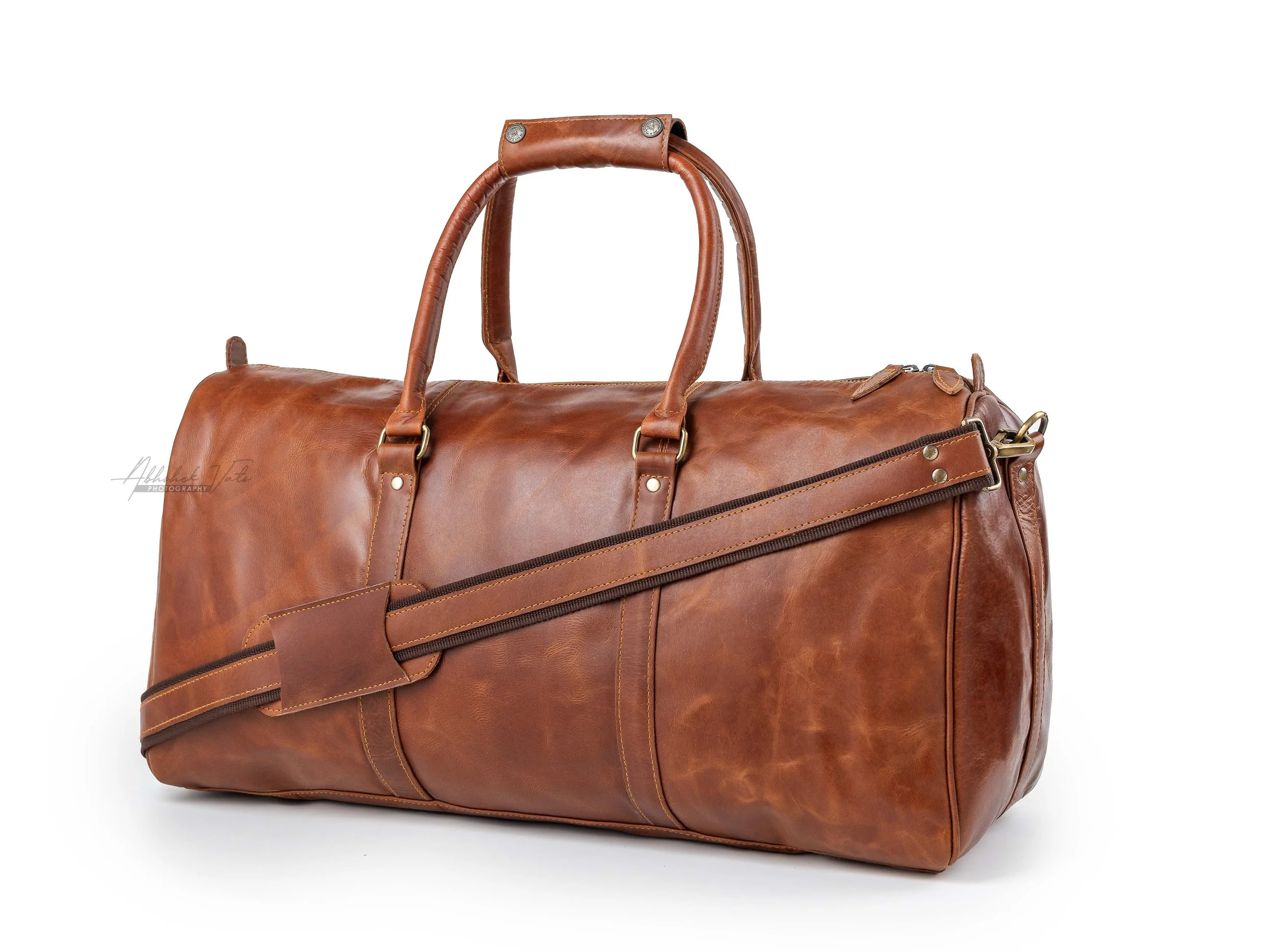 A large brown leather duffel bag with handles and zipper details on a white background.