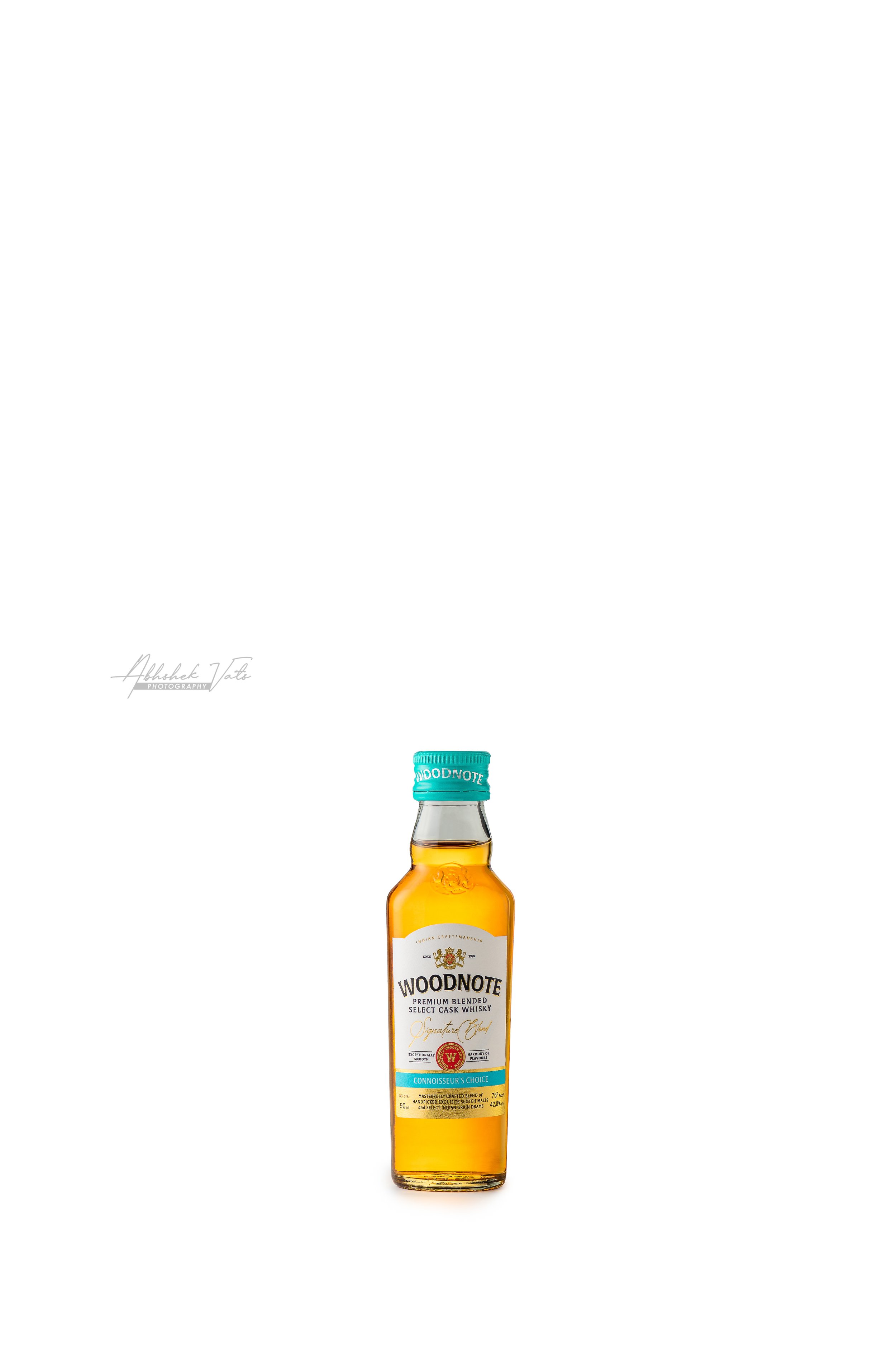 A bottle of Woodnote premium blended whisky with a turquoise cap and white label, centered on a white background.