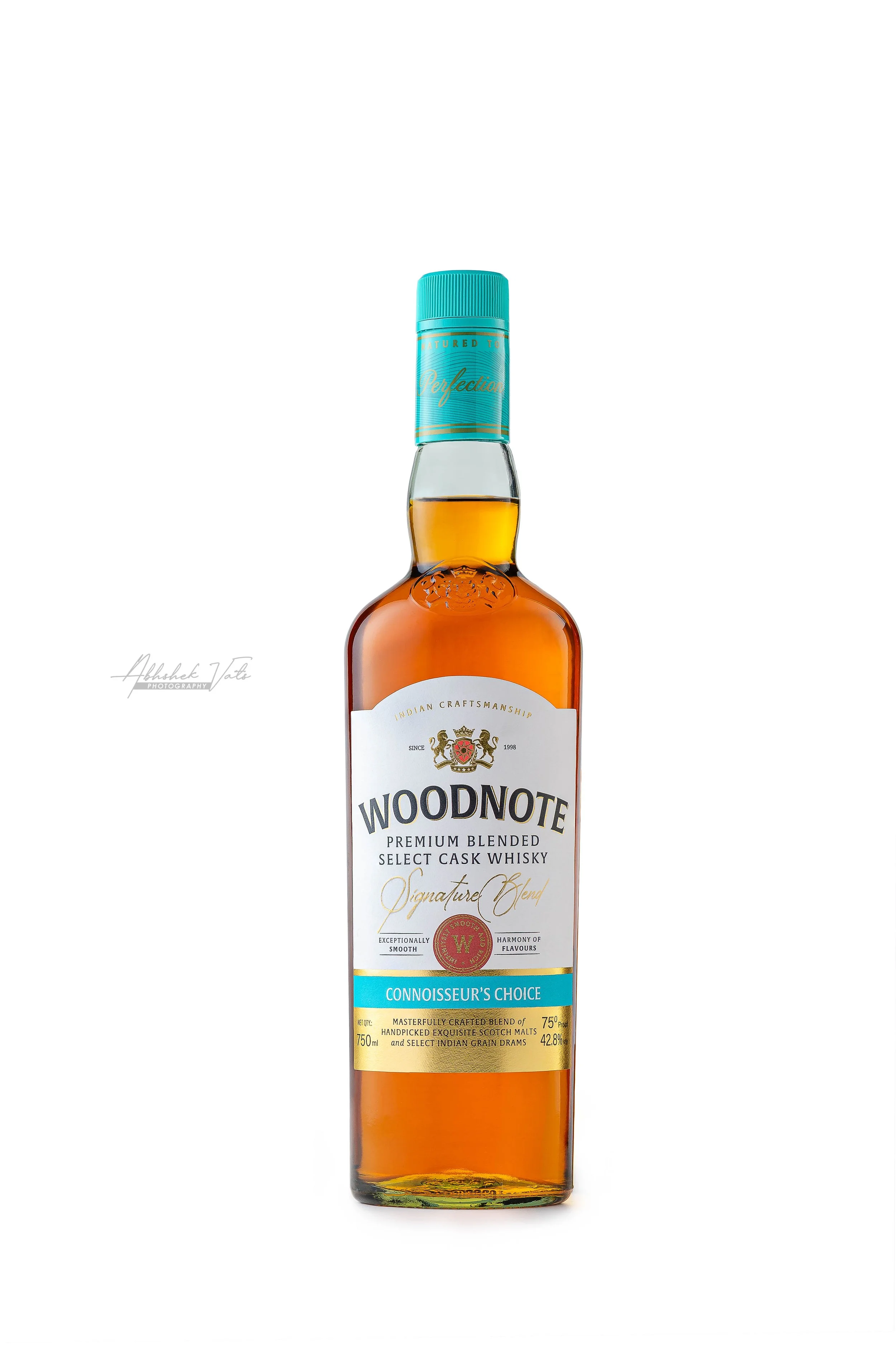 Bottle of Woodnote Premium Blended Whisky with a light blue cap and a white label, featuring gold and blue accents.