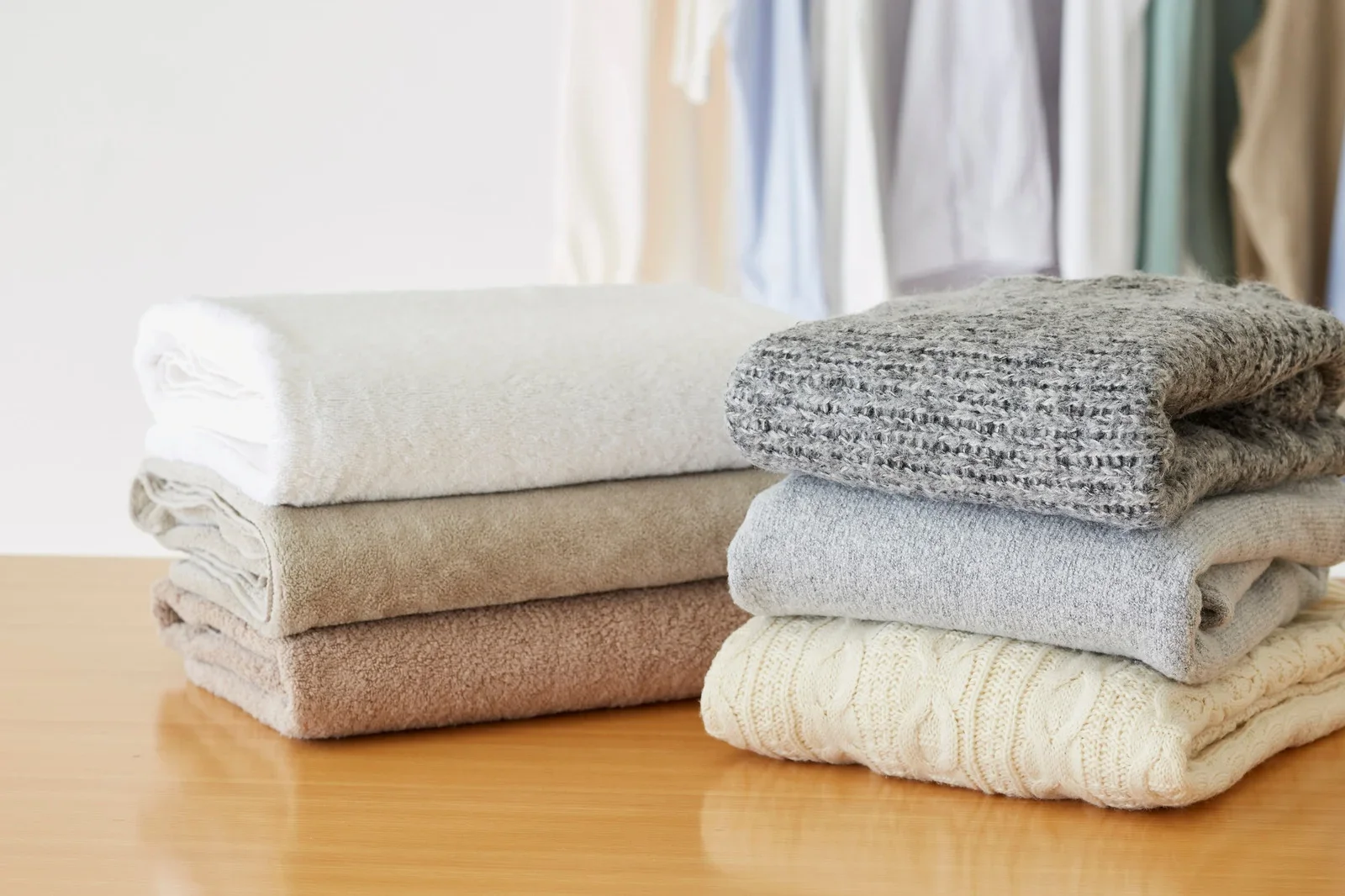 Neatly folded neutral-coloured textiles stacked on a wooden surface