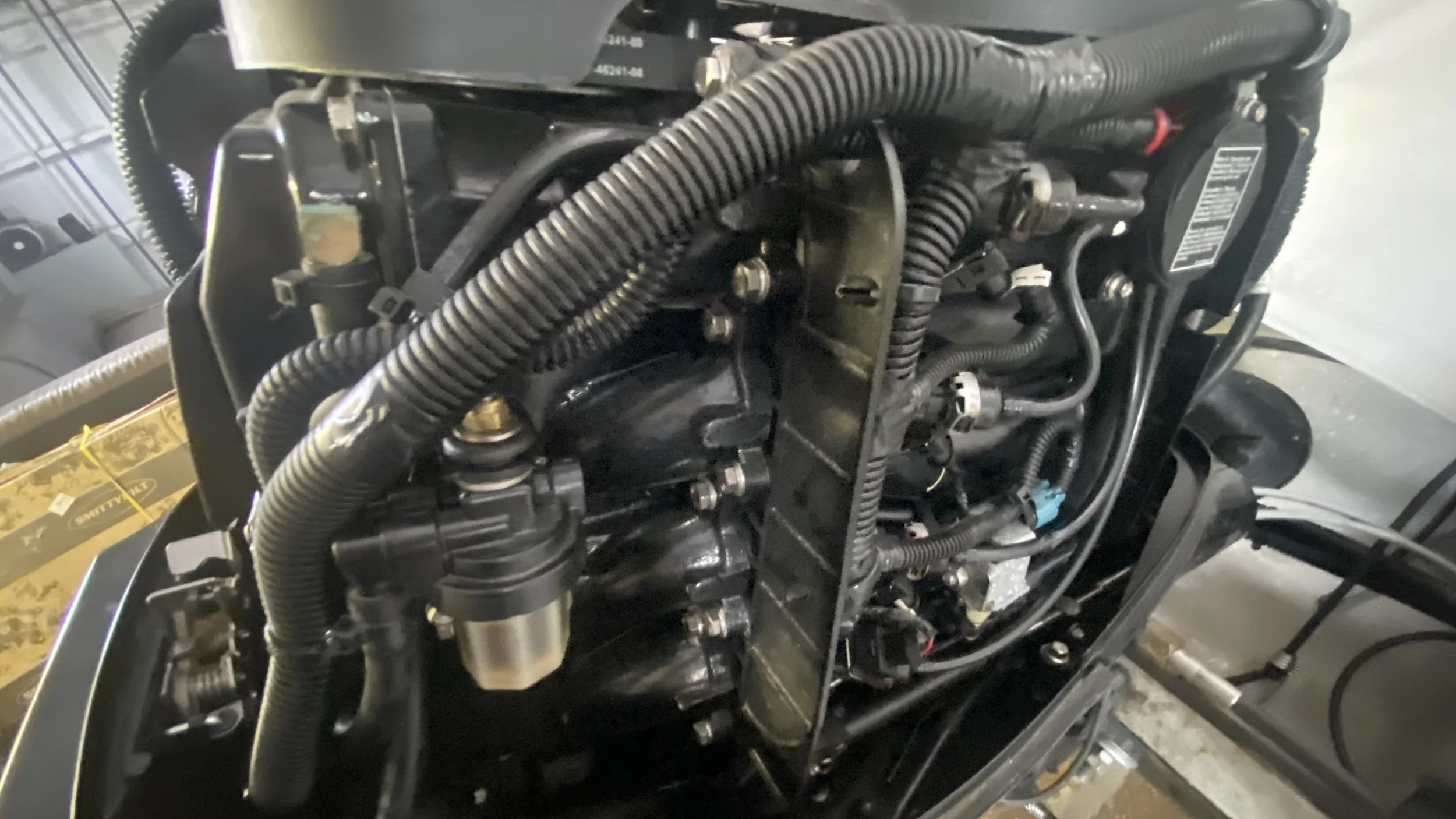 Close-up of a vehicle's engine with various hoses, cables, and mechanical components.