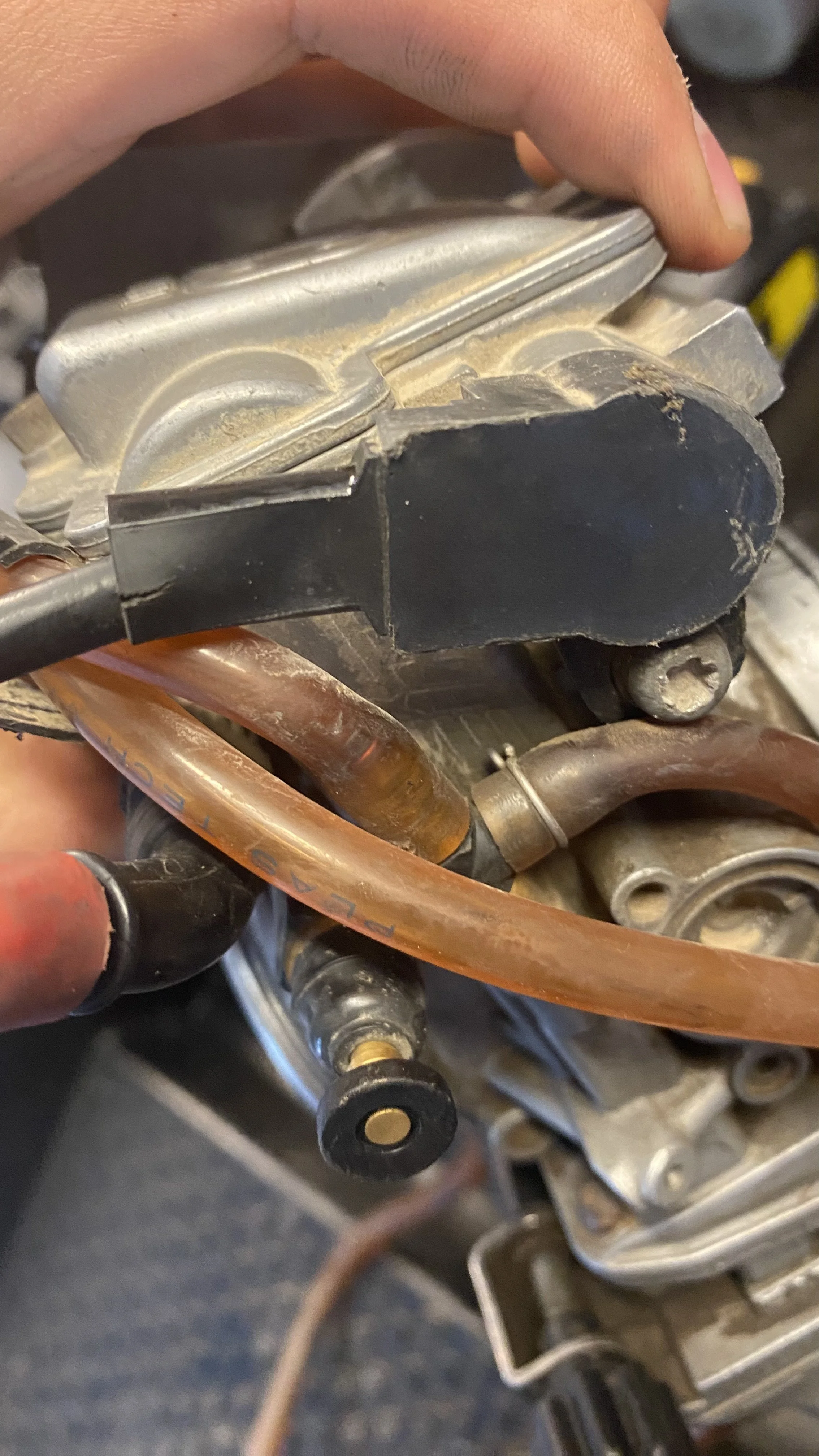 Close-up of a motorcycle engine component showing metal parts, wires, and hoses.
