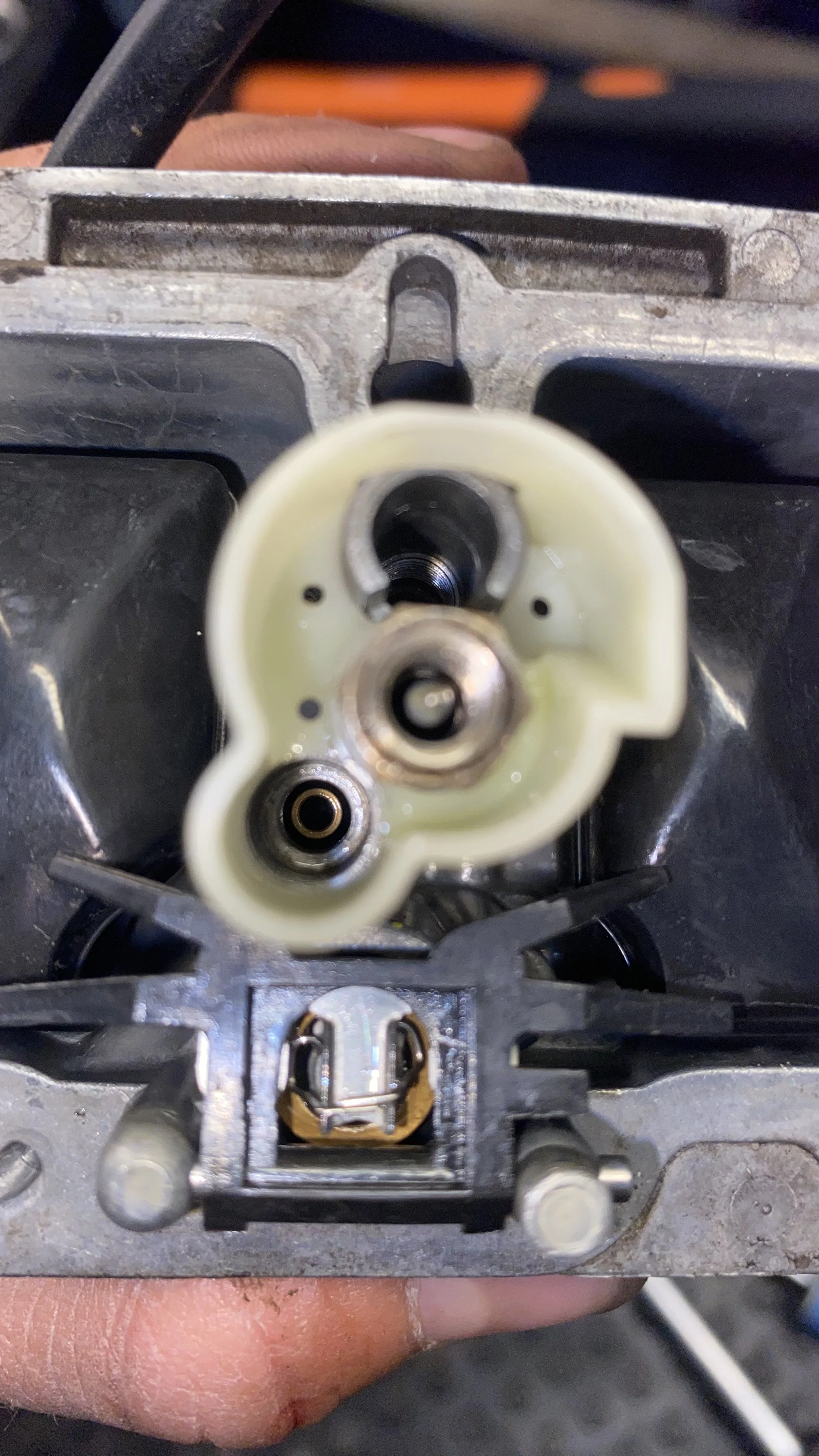 Close-up view of internal components of a carburetor, showing the throttle plate and the fuel intake passage.