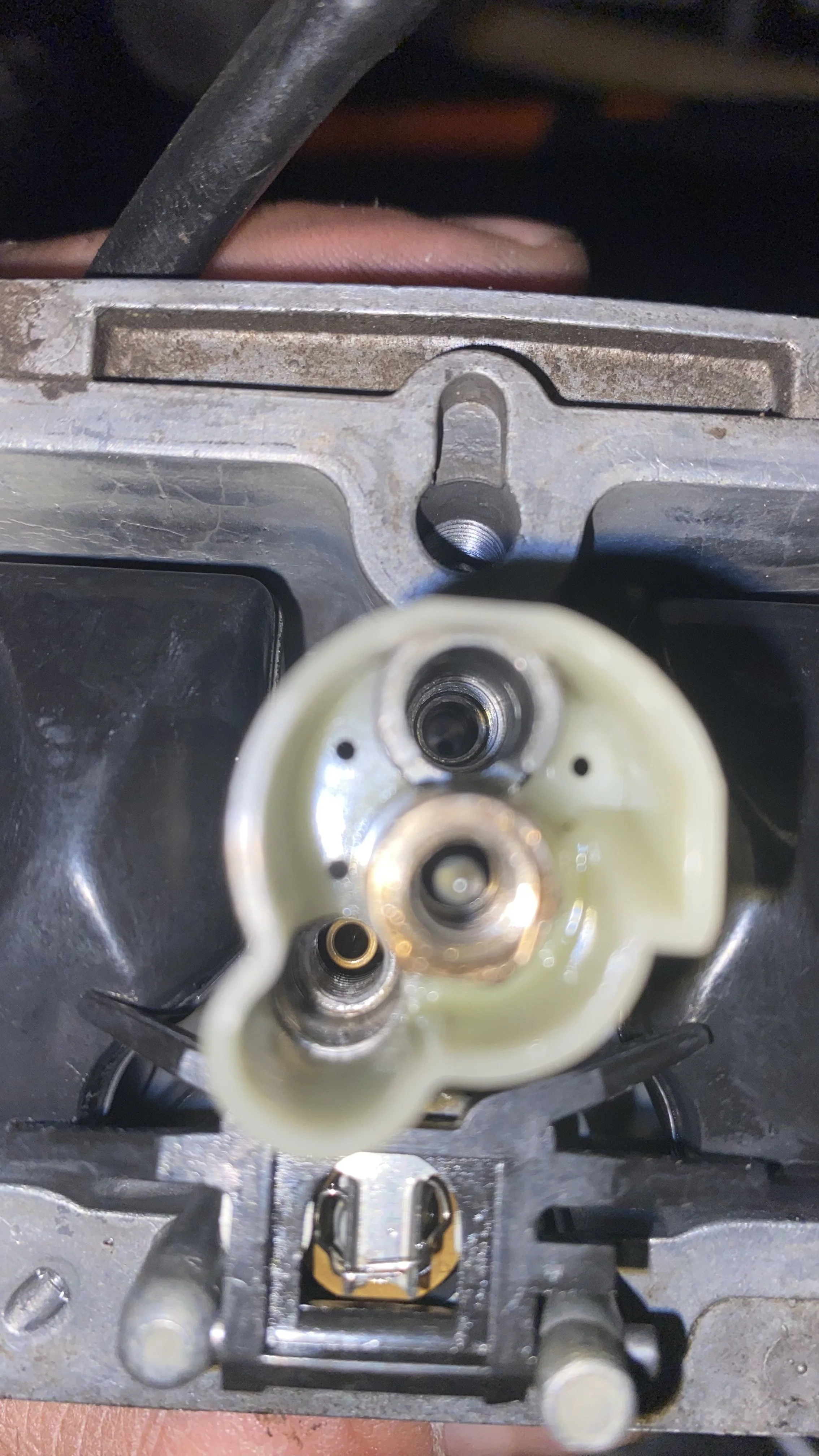 Close-up of a carburetor with visible internal components and openings.