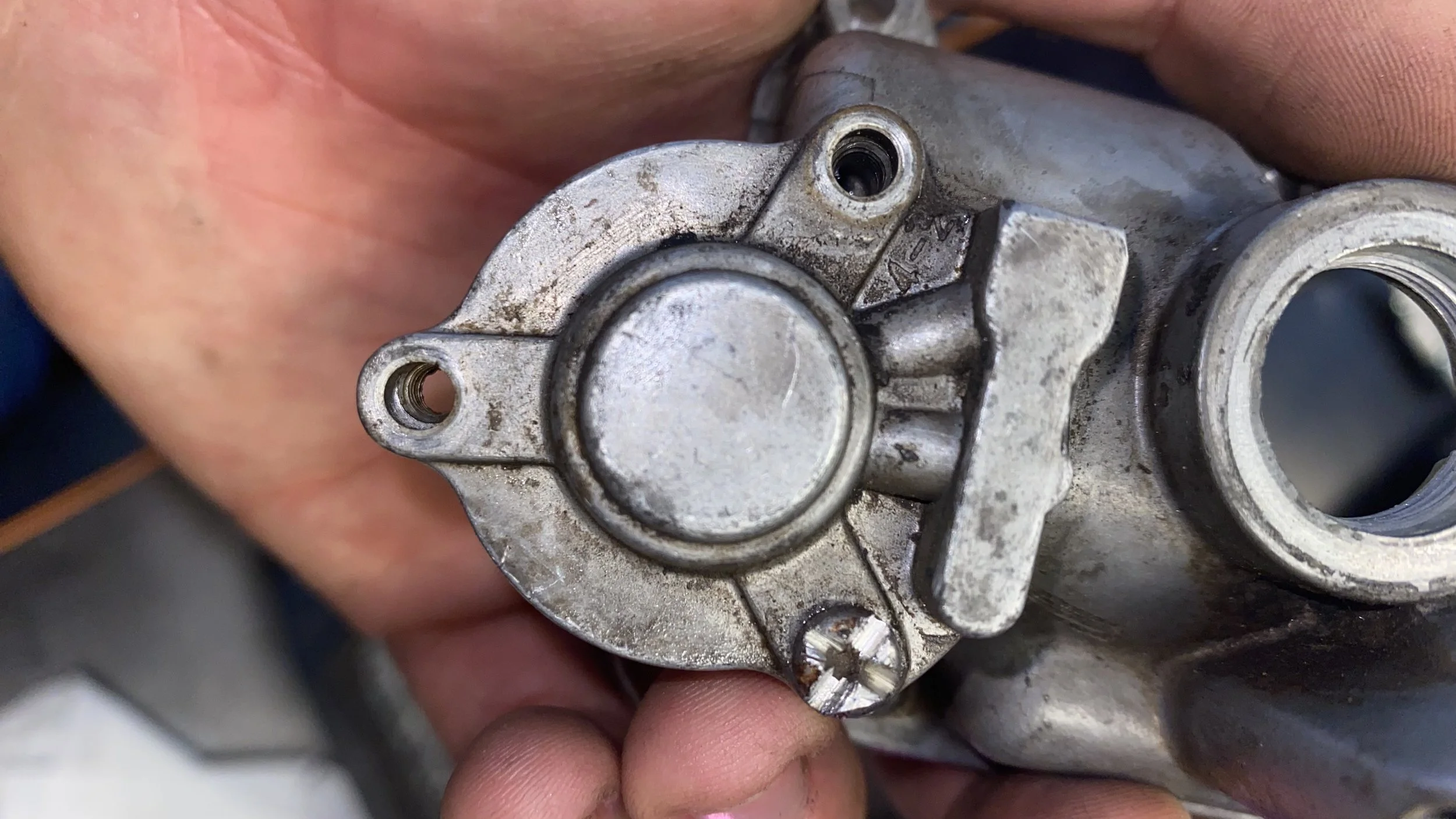 Close-up of a metallic mechanical part, possibly an engine component, being held by a person's hand.