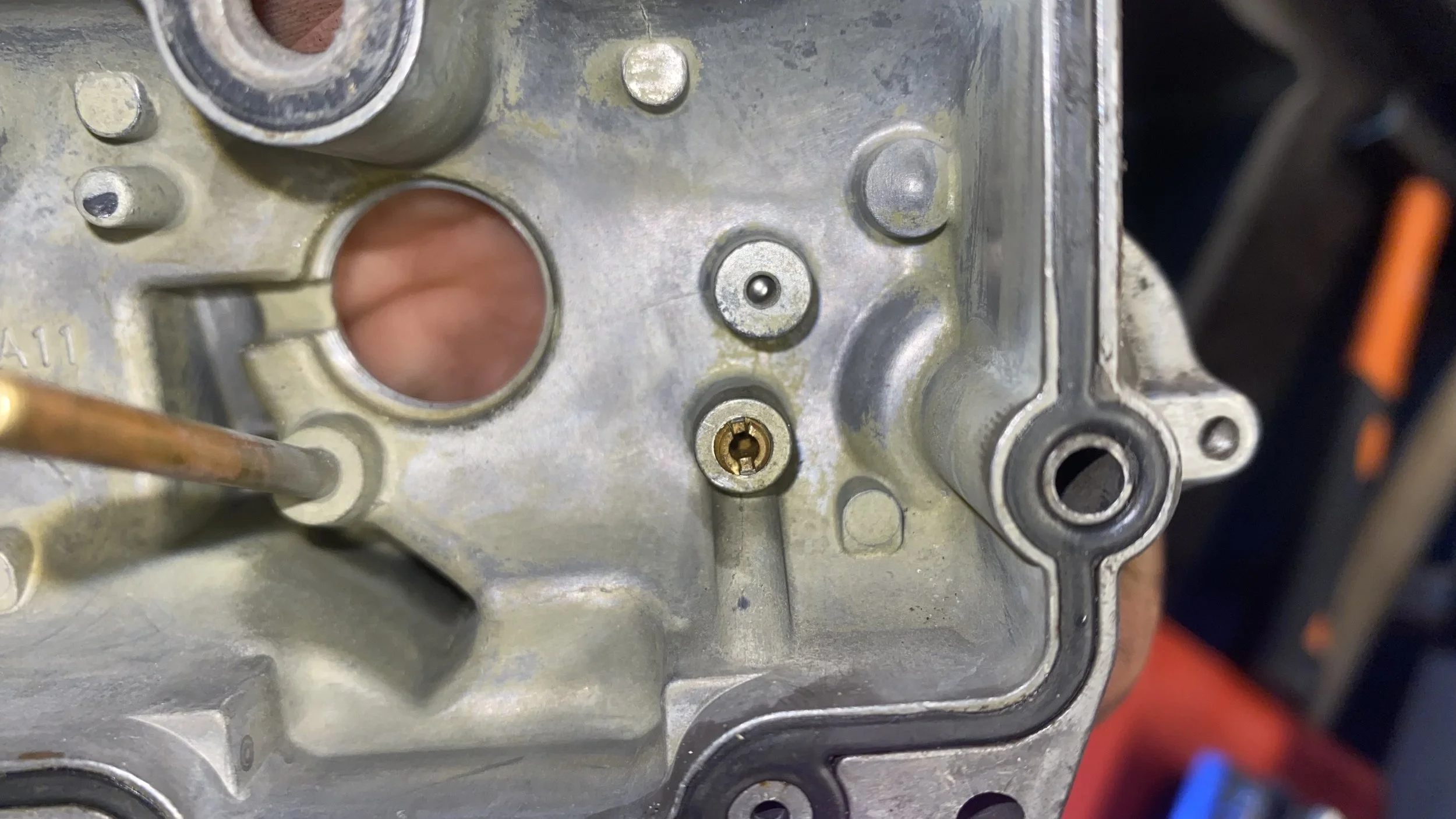 Close-up of a metallic carburetor with various screws, pipes, and openings, no specific objects or labels visible.