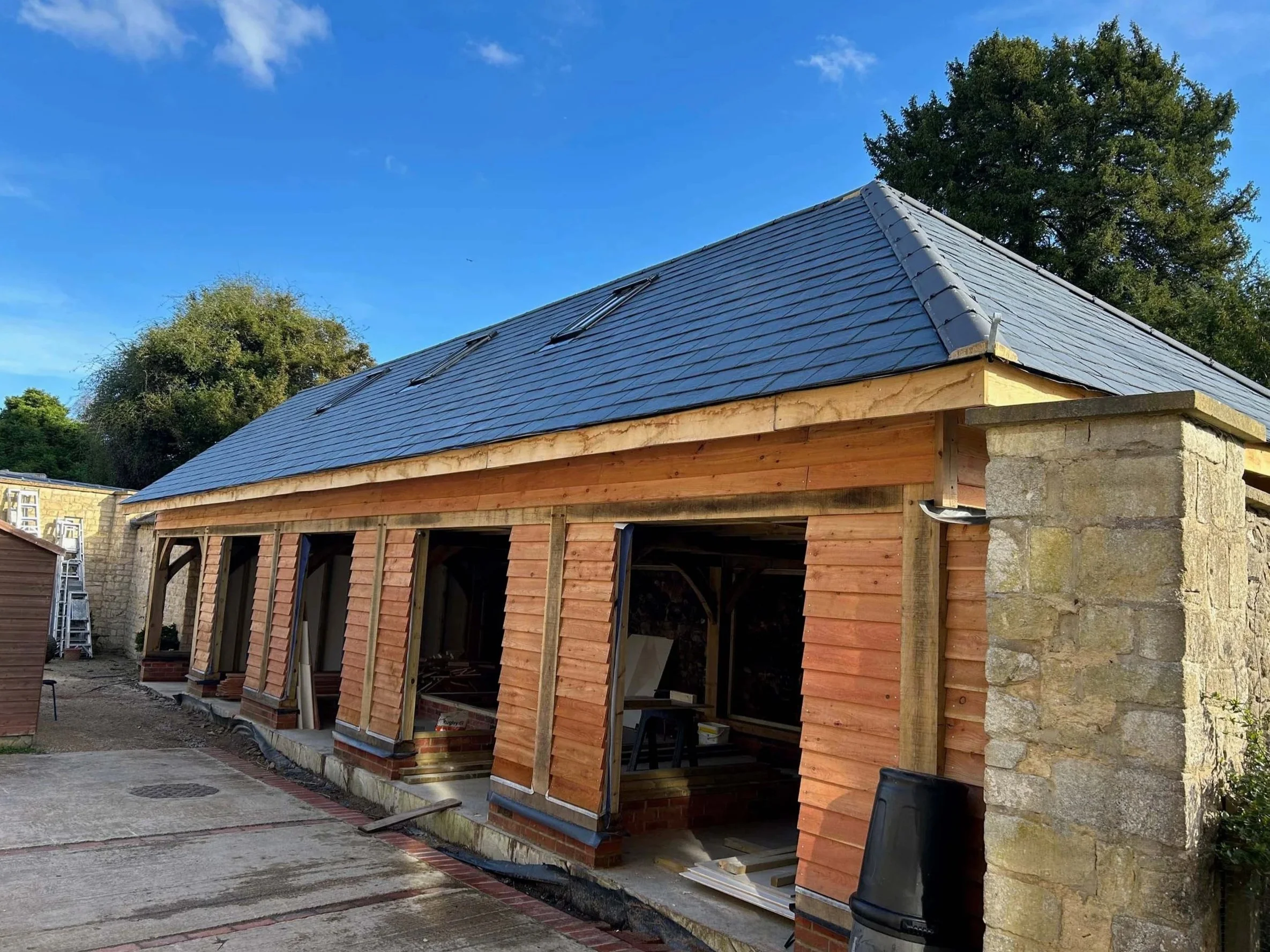 Under-construction building with wooden framing, brick bases, and slate roof.