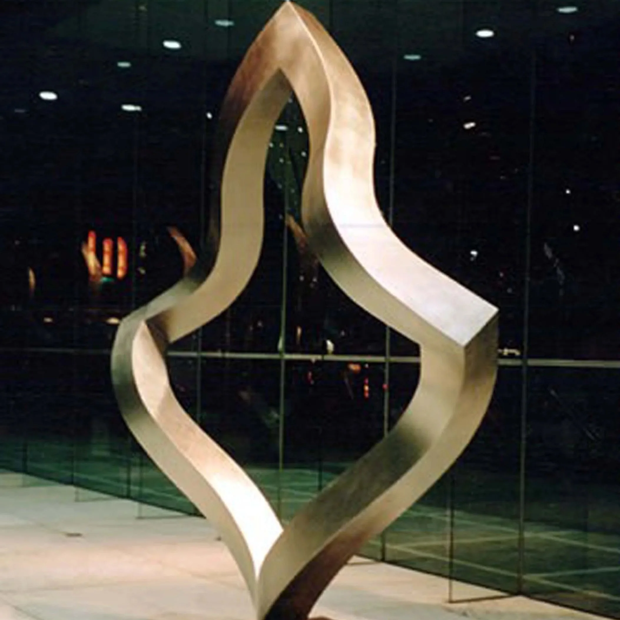 A modern staircase with a curved, metallic handrail in a brightly lit interior space.